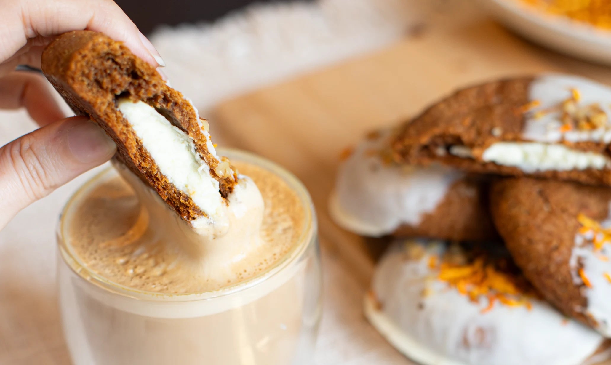 Person dipping a Carrot Cake Cookies into a cup of coffee with other cookies in the background