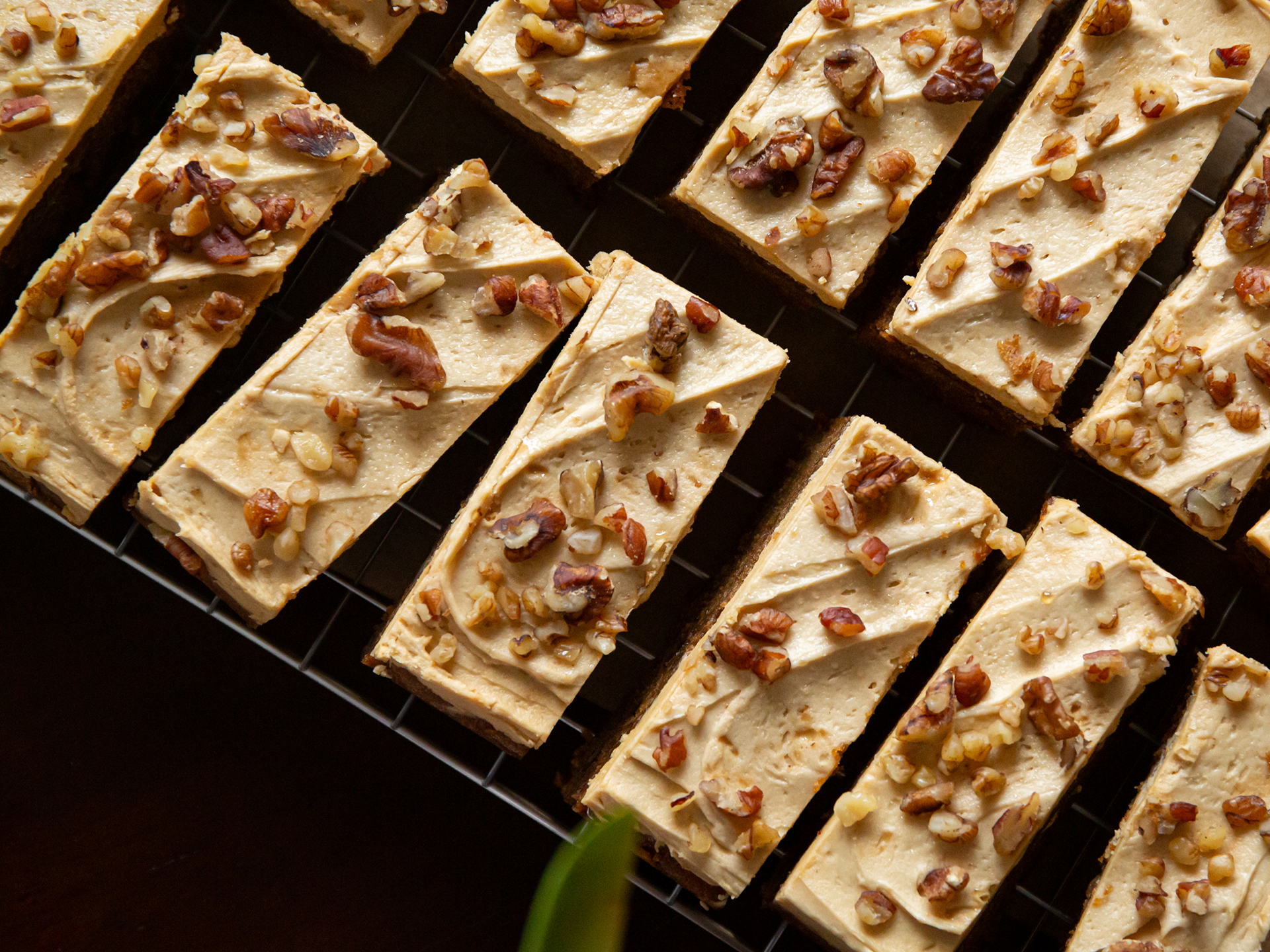 Rectangular Coffee Pecan Walnut Cake with a creamy topping and pecans on a dark surface