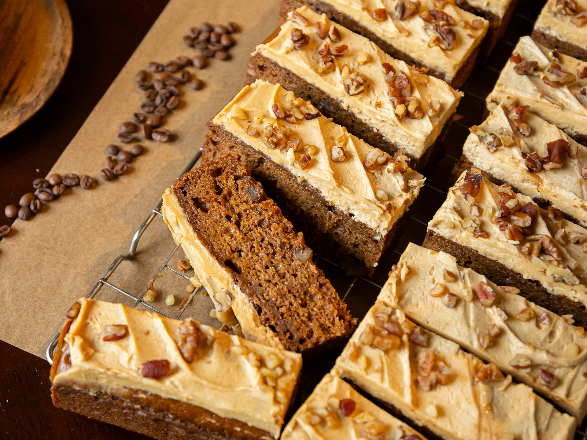 Coffee Pecan Walnut Cake with frosting and pecans on a cooling rack with coffee beans around.