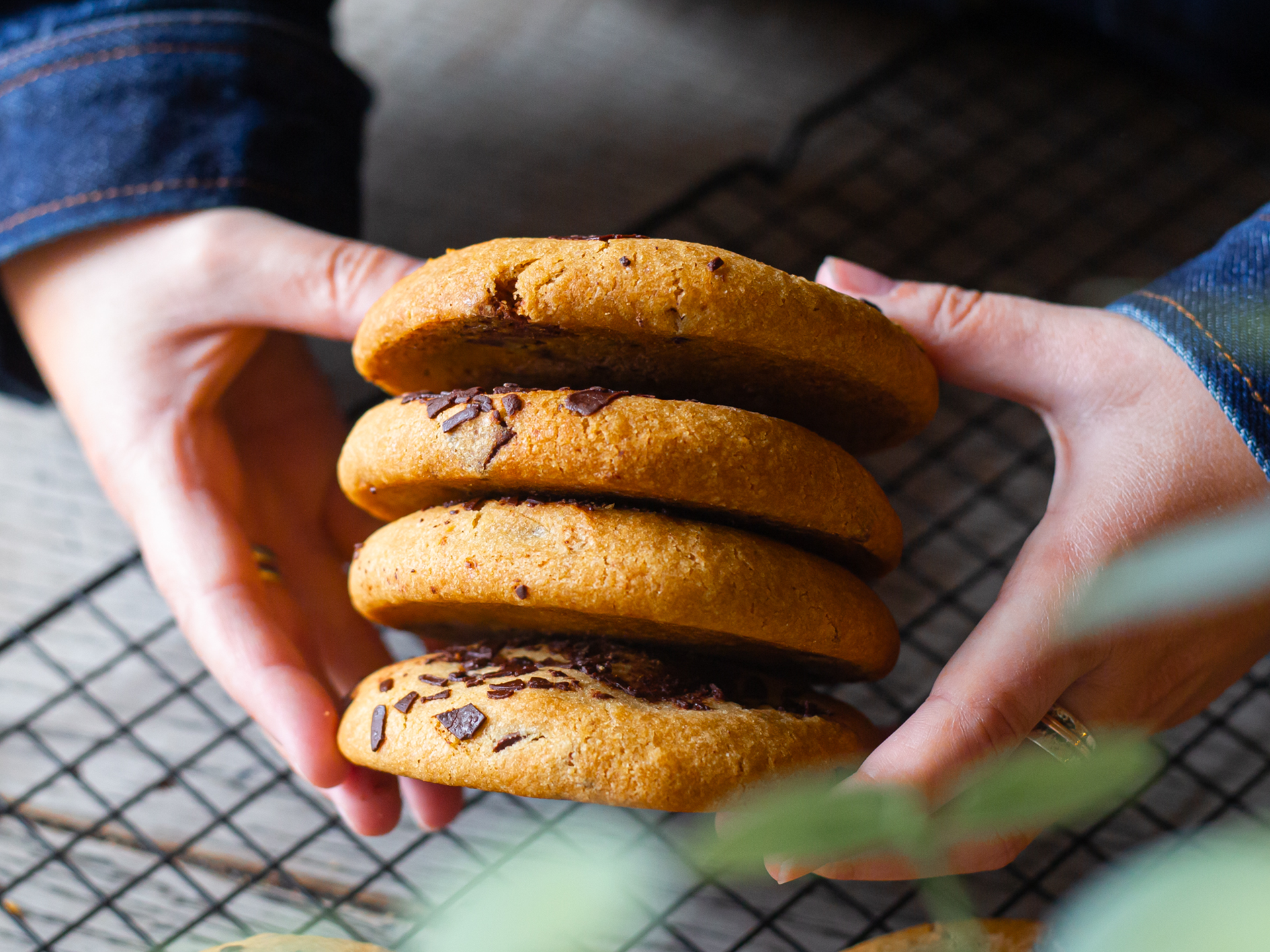 Hands holding a stack of double chocolate chip cookies