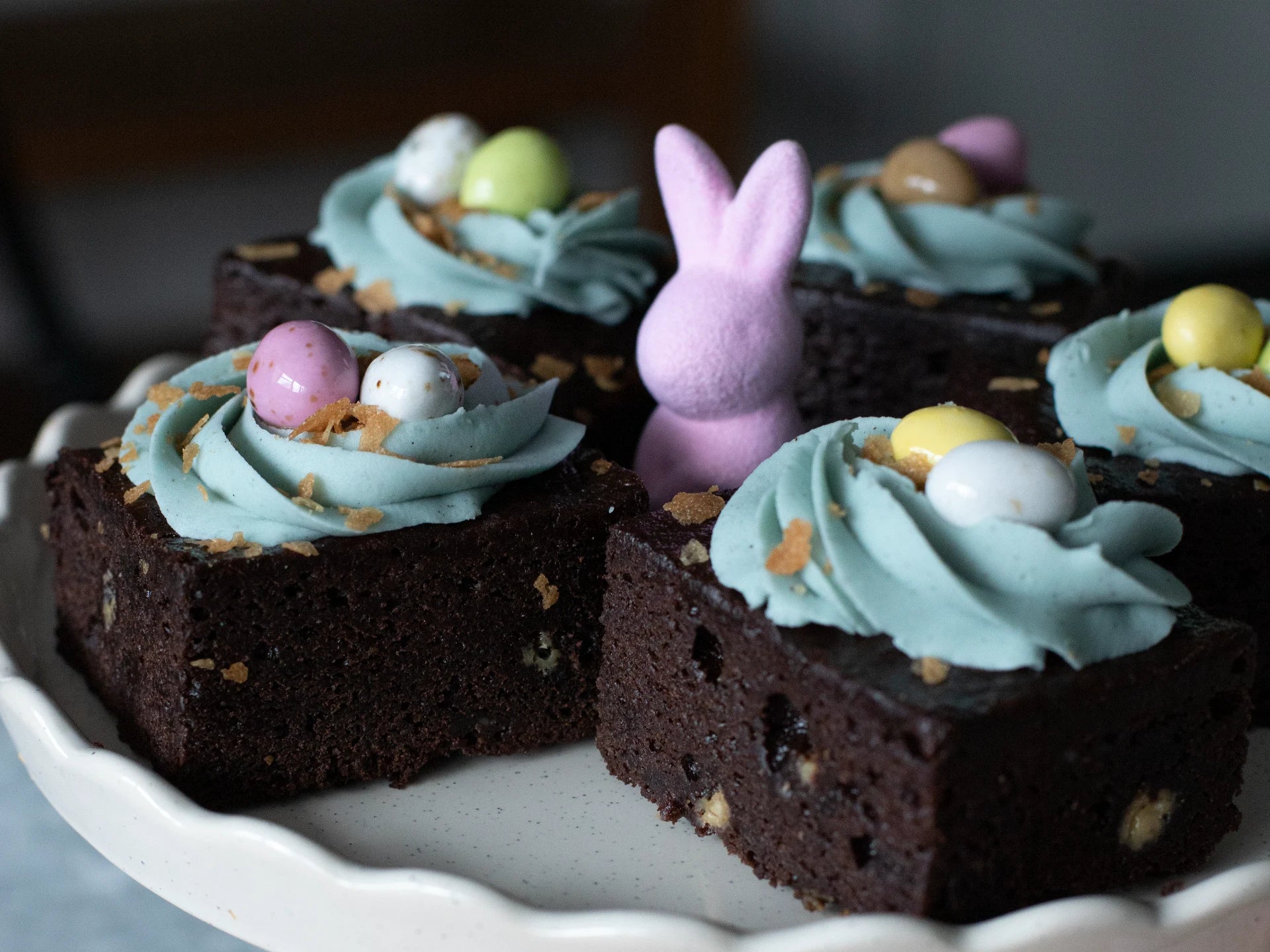 Chocolate Easter Nest Cake with green frosting and decorative eggs on a white plate.