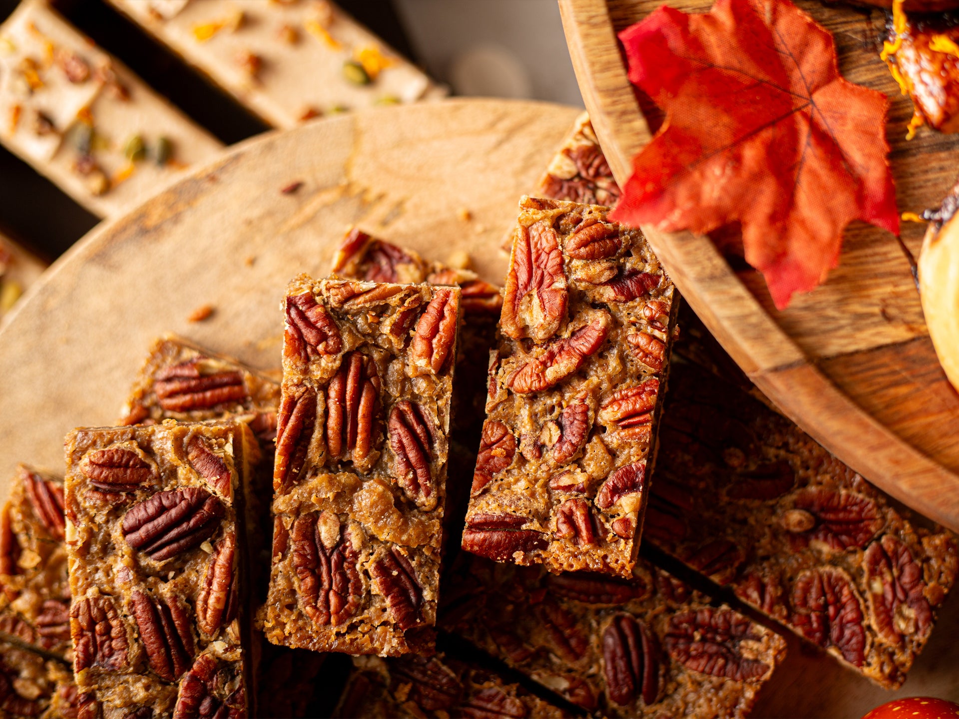 Pecan pie bars on a wooden board with autumn leaves