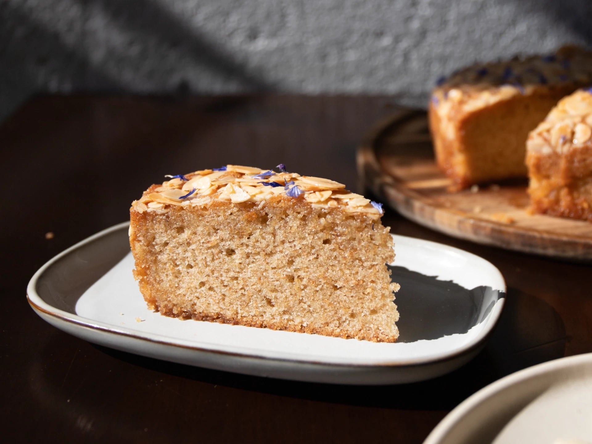 Slice of Honey Lavender Almond Round Cake on a plate with a blurred background