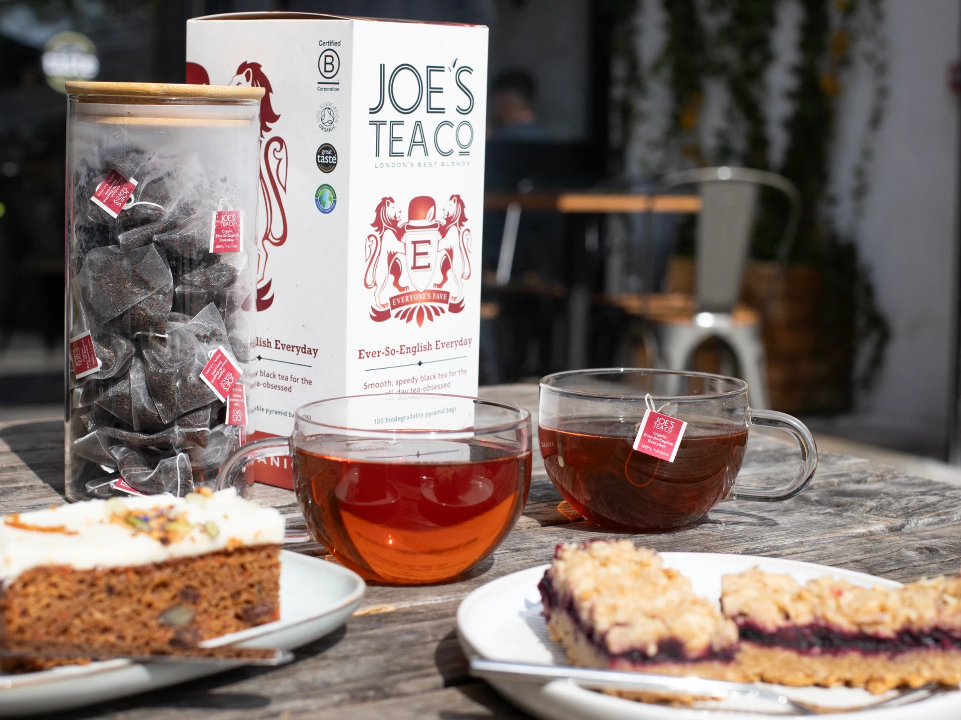 Two cups of Joe's Tea Co - Ever-So-English Breakfast tea with a box of Joe's Tea Co. on a table with pastries.