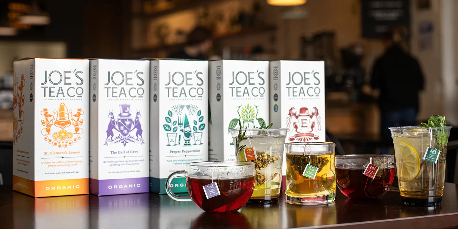Joe's Tea Co. tea boxes and glasses of tea on a table with a blurred background