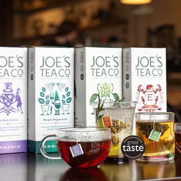 Joe's Tea Co. tea boxes with cups of tea on a reflective surface.