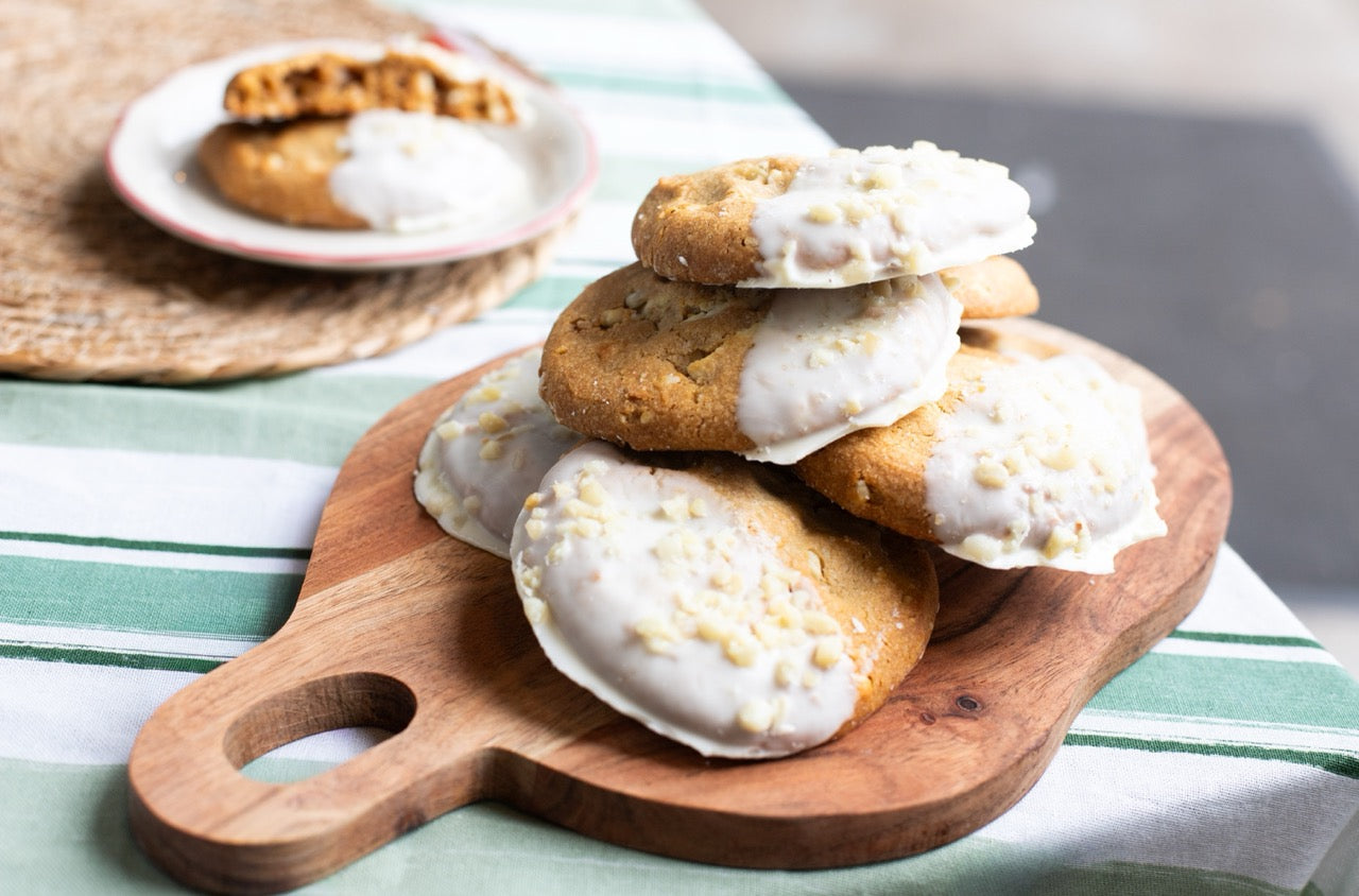Stack of Miso Cookies with white icing on a wooden board on a striped tablecloth