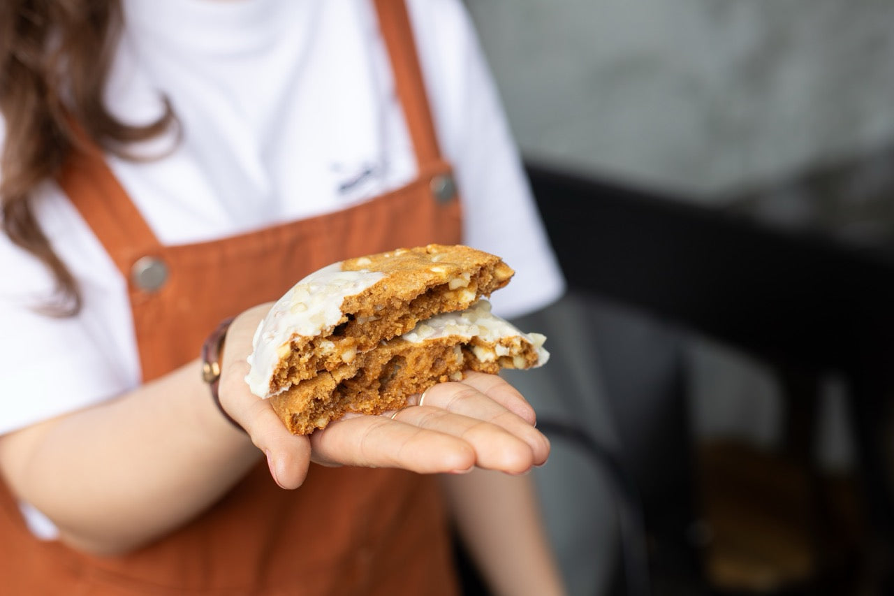 Person holding a Miso Cookies with cream filling, wearing an apron.