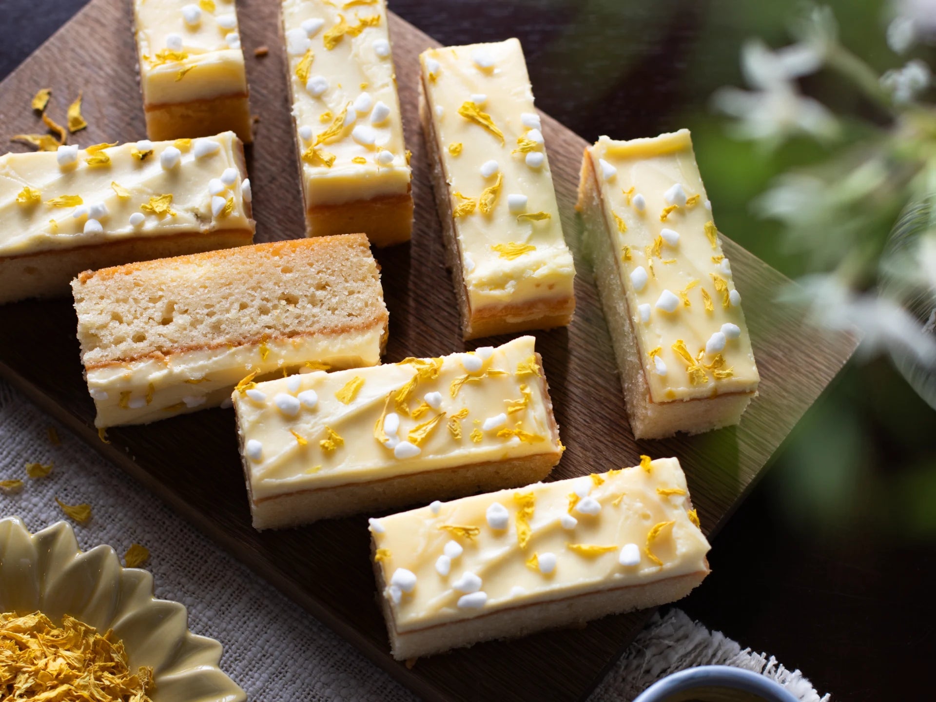 Sicilian Lemon Meringue cake slices with white frosting and yellow decorations on a wooden board.