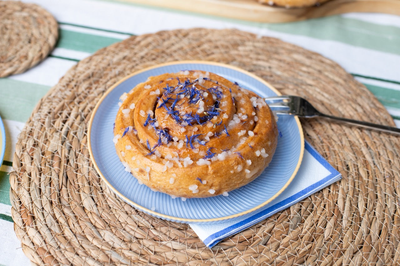Sticky Lemon Drizzle on a blue plate with a fork on a woven placemat