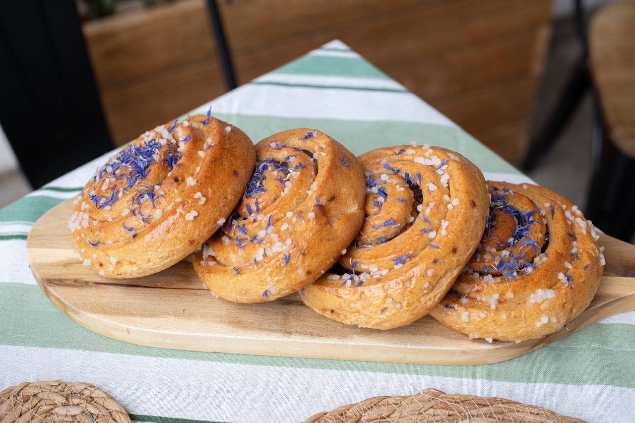 Sticky Lemon Drizzle with blue sprinkles on a wooden board on a striped tablecloth.