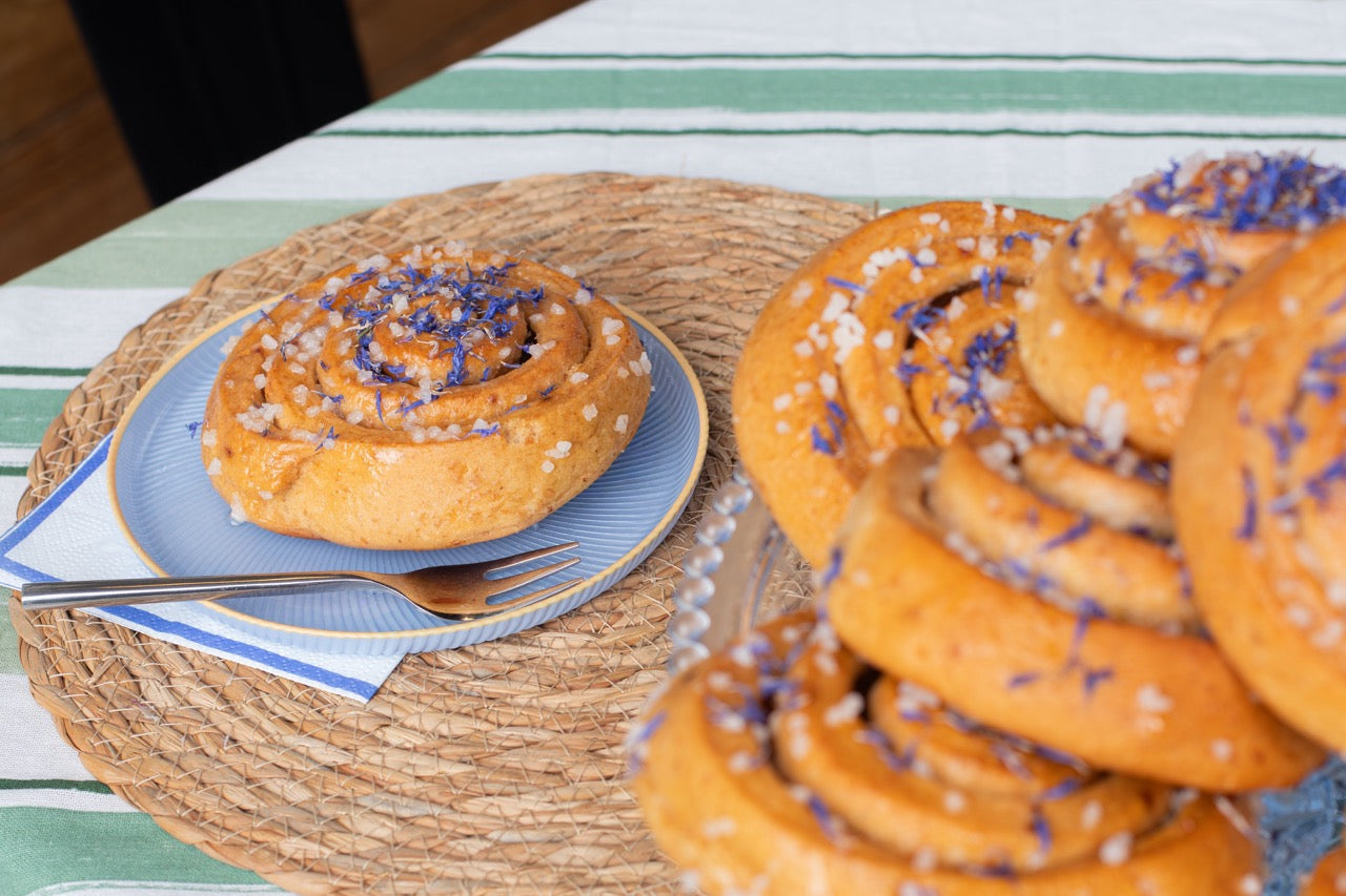 Sticky Lemon Drizzle buns with purple sprinkles on a woven table mat