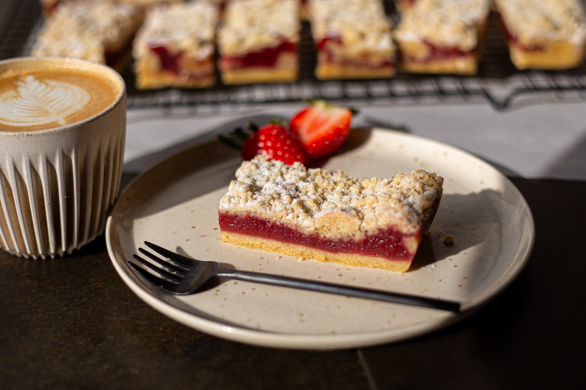 A slice of the side of our strawberry shortcake bar: a layer of shortbread, a layer of strawberry jam and final layer of crumble topping