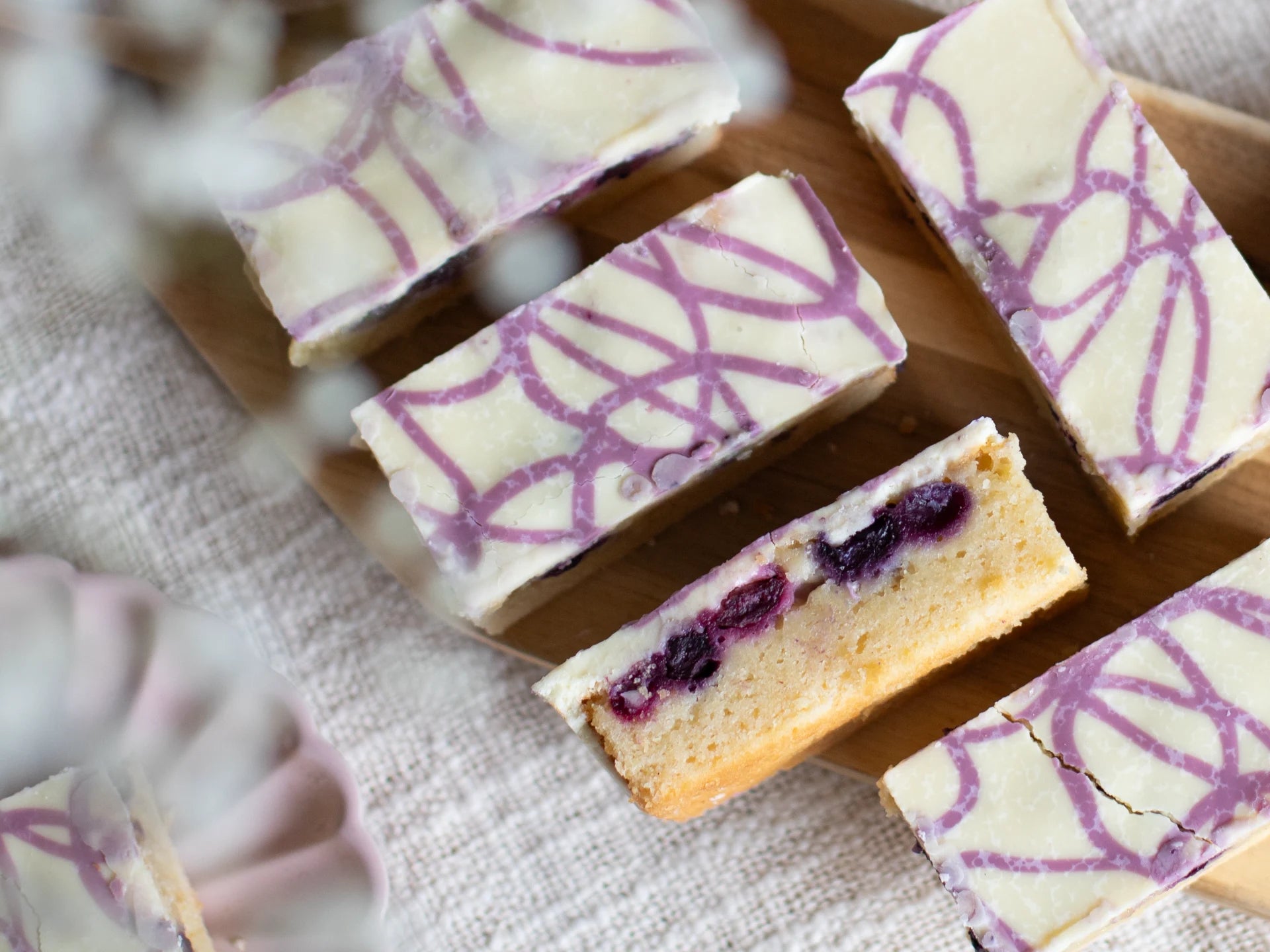 White Chocolate Blueberry Blondie with purple patterns on a wooden board