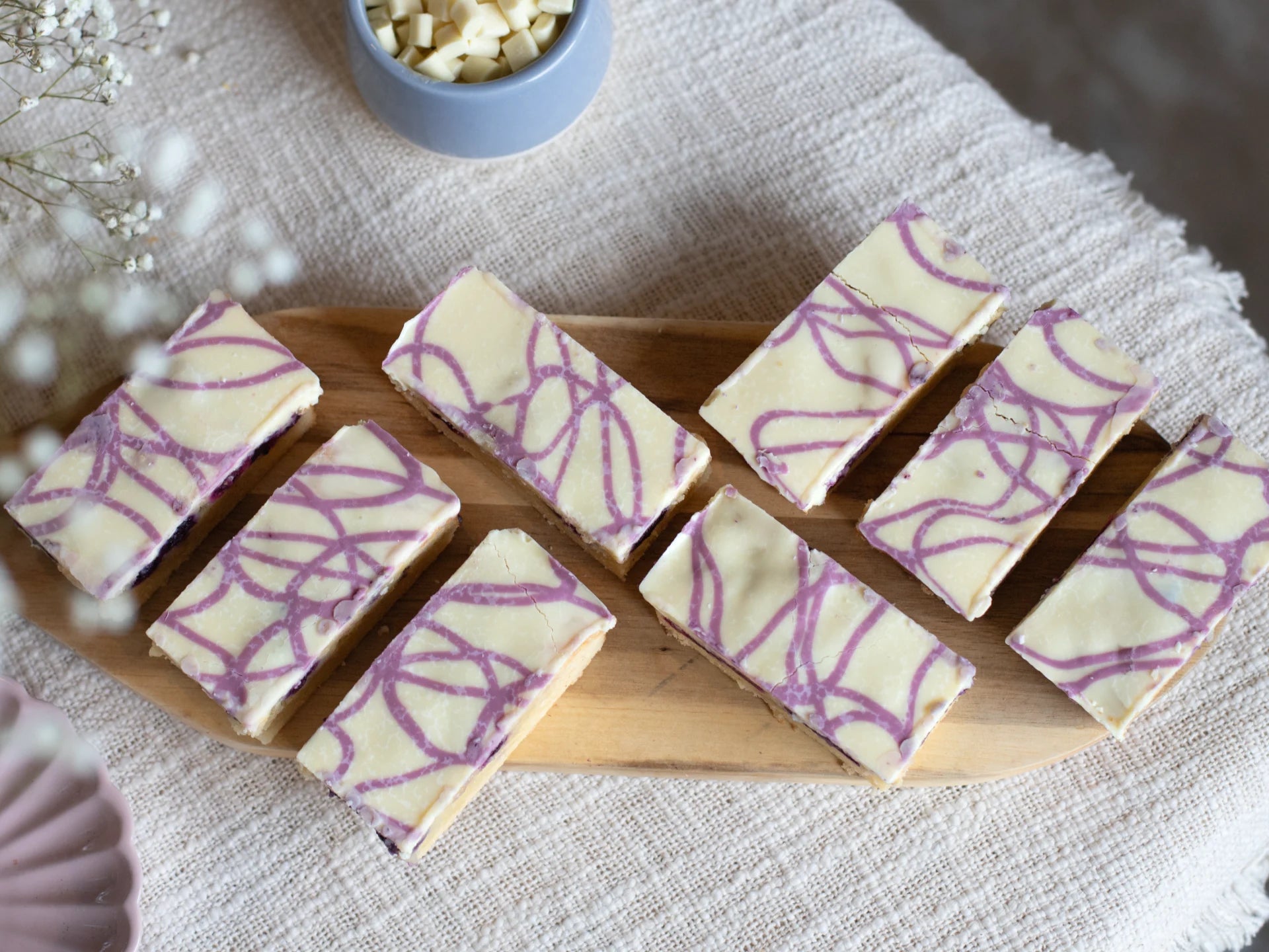 White Chocolate Blueberry Blondie with purple patterns on a wooden board.