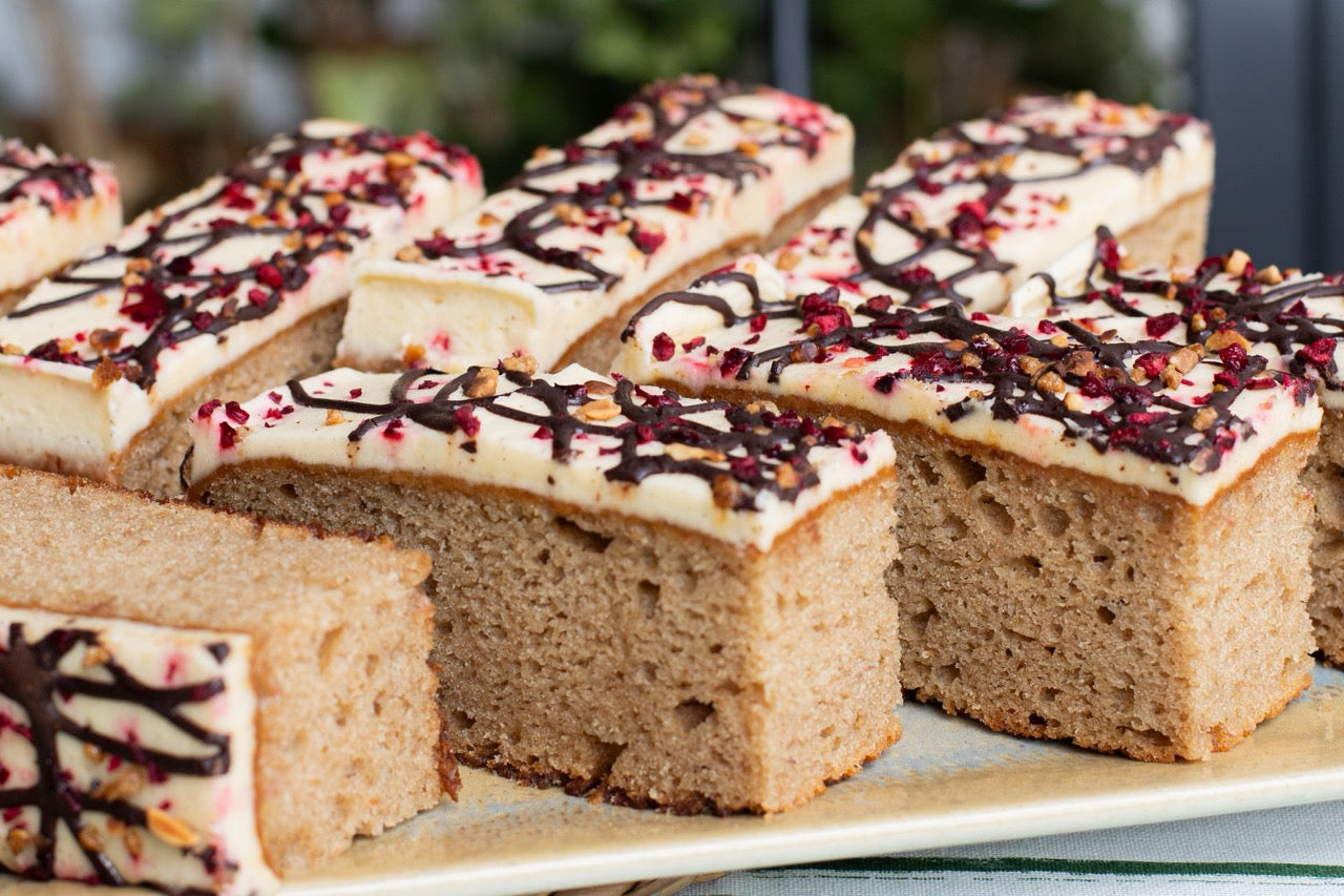 Sliced Banana Split cake with white frosting and chocolate drizzle on a plate