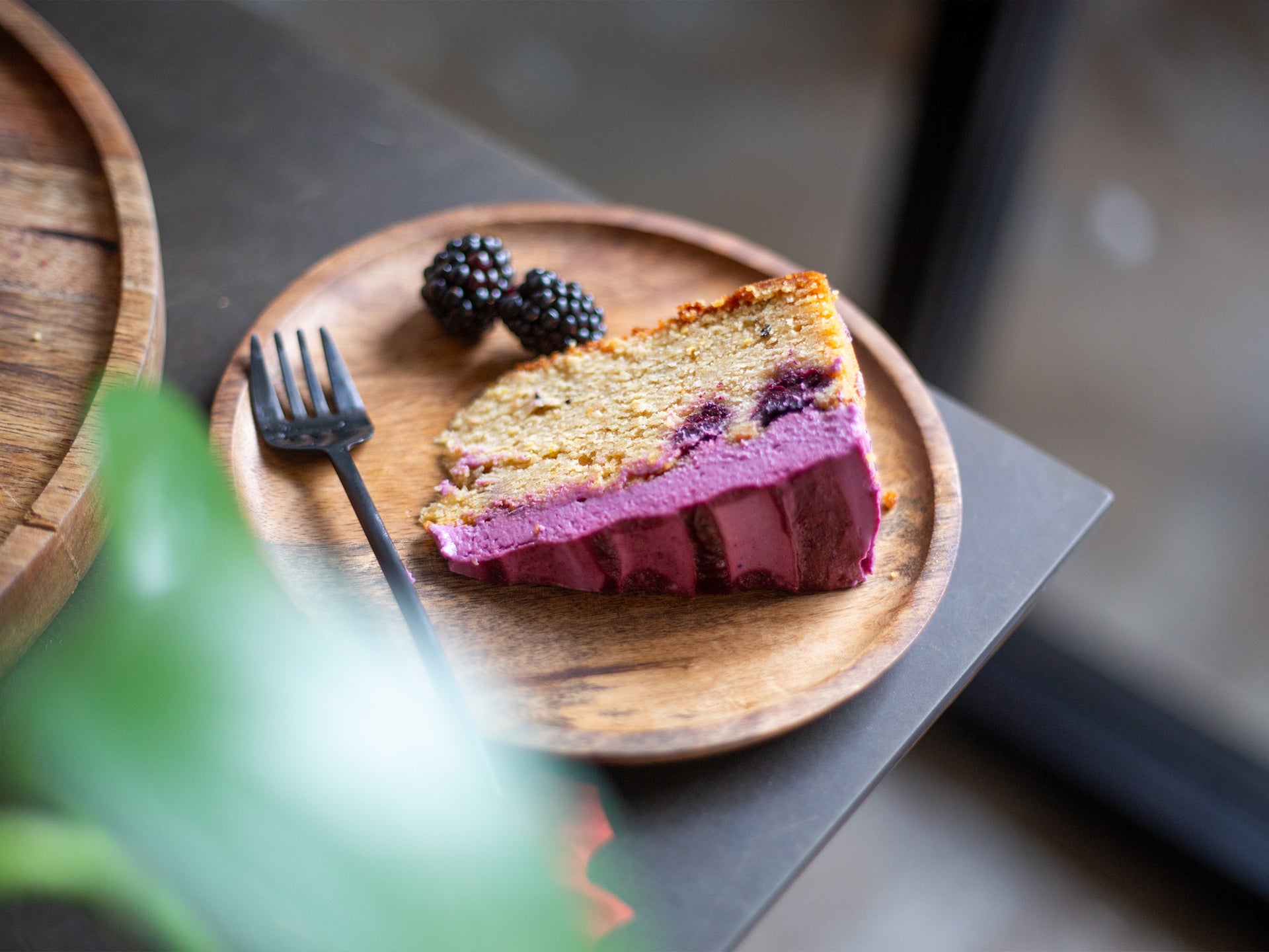 A slice of wholesale blackberry & earl grey sponge cake with purple frosting