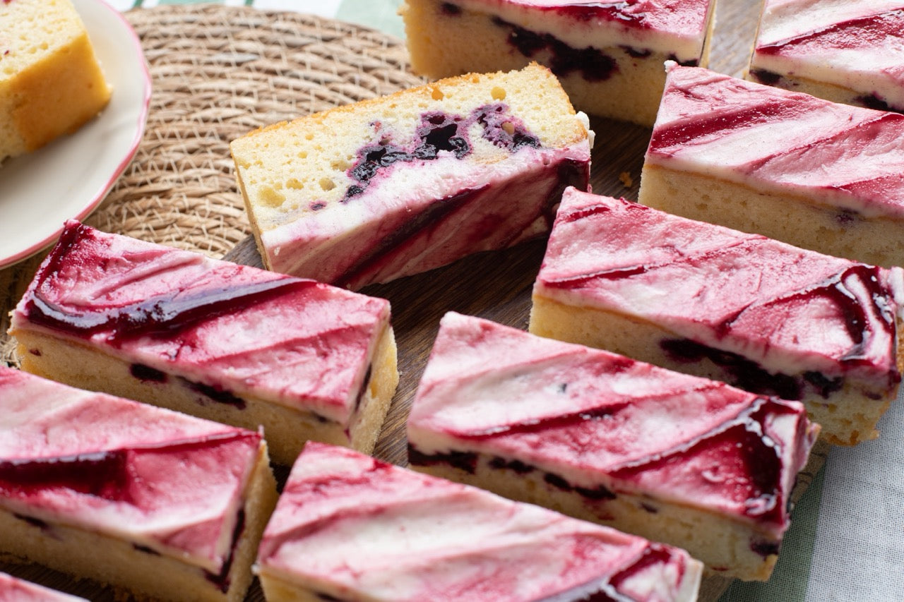 Slices of Blackcurrant Ripple cake with a red and white swirl on a wooden board.