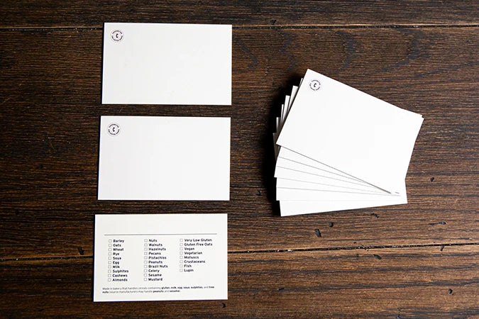 Blank white product display cards with space for writing the product name on the front and a list of allergens to tick on the back