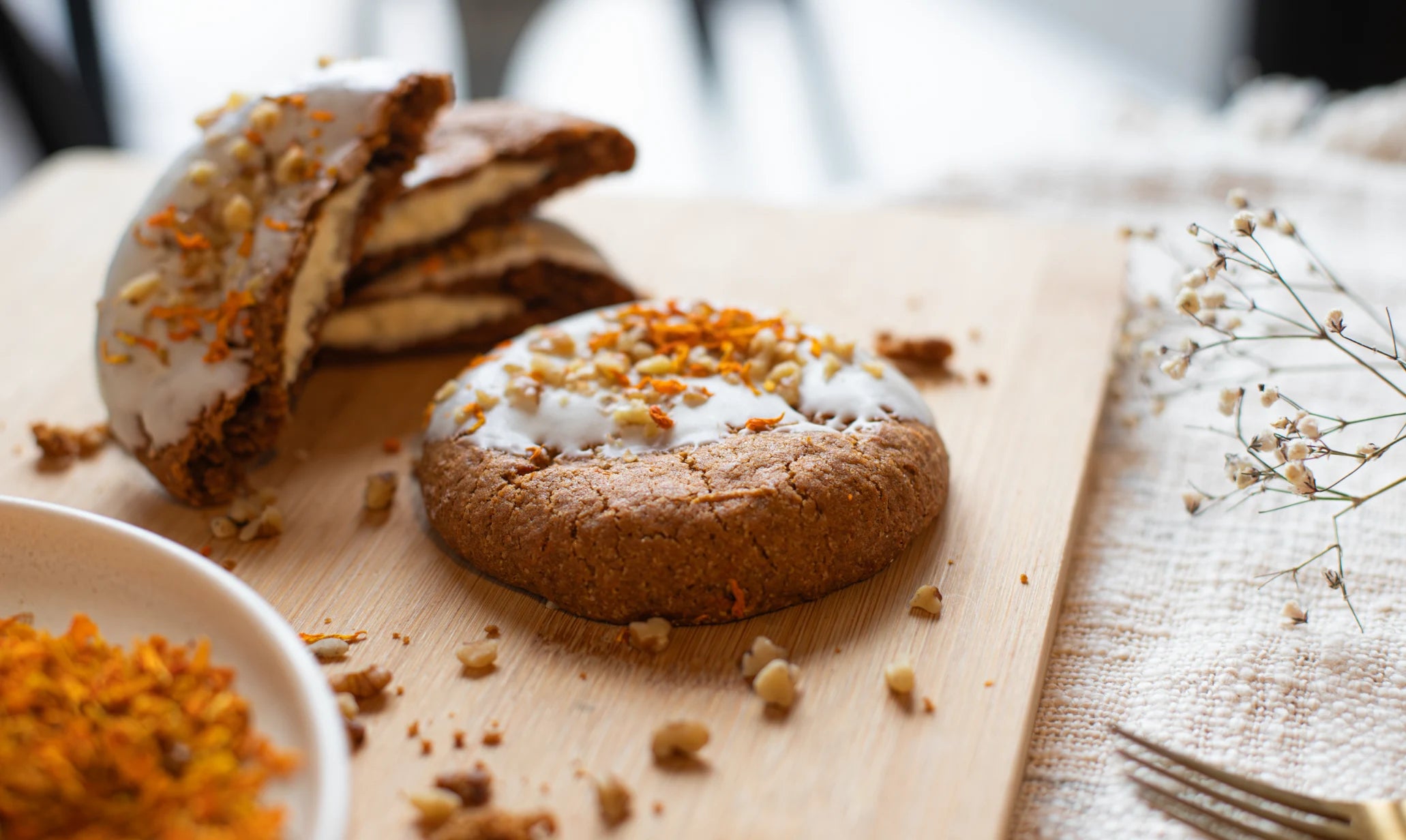 Carrot Cake Cookies with white frosting and sprinkles on a wooden board with a blurred background