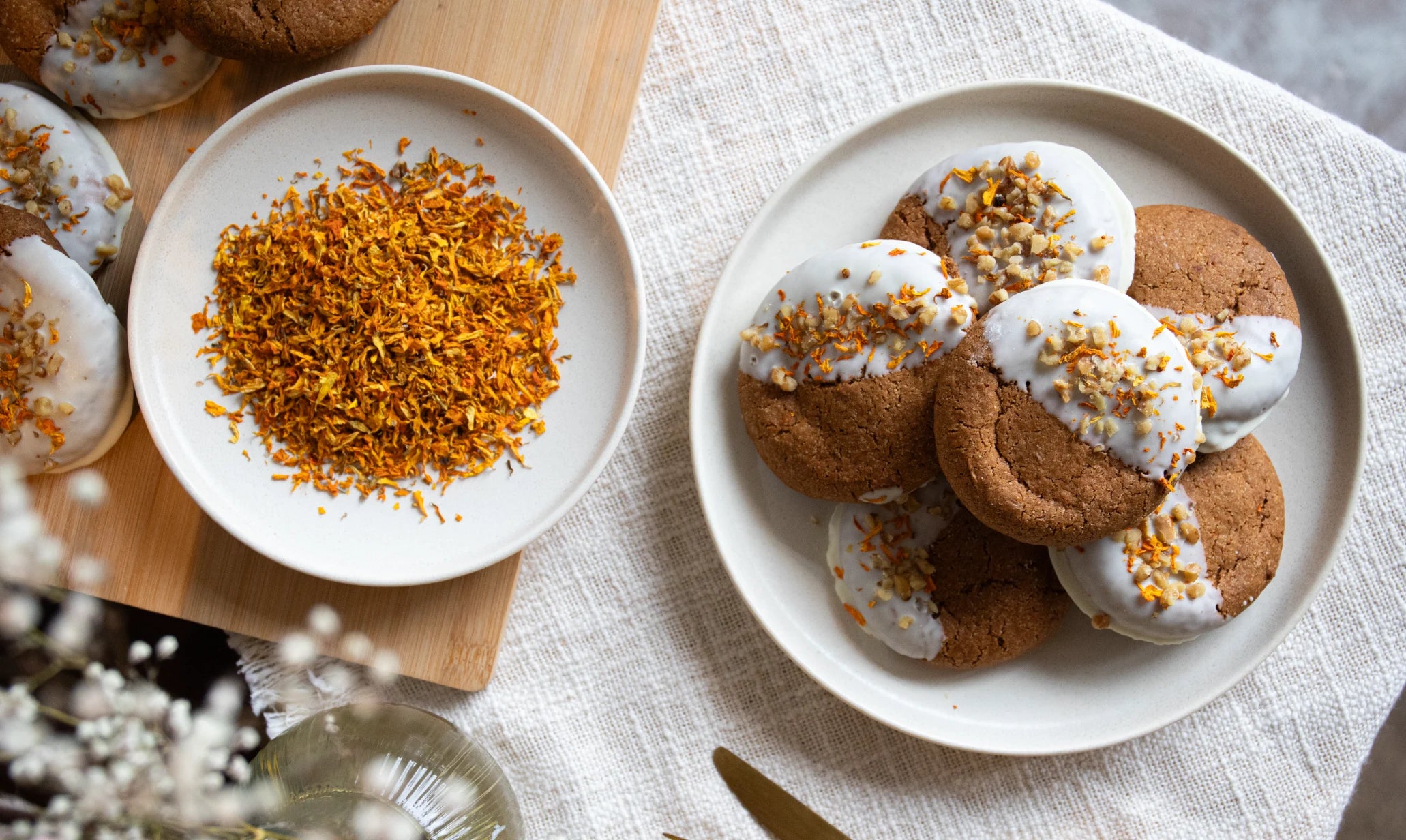 Carrot Cake Cookies with white icing and gold sprinkles on a white plate, placed on a light-colored surface.