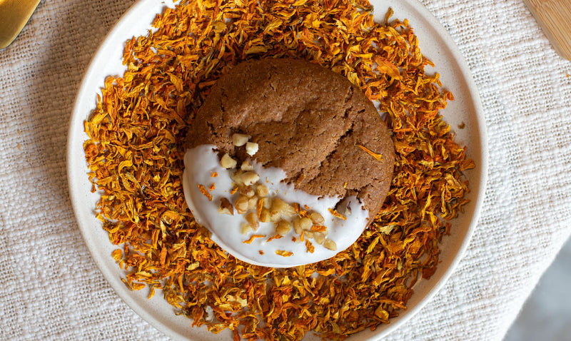 Carrot Cake Cookies, white cream, and nuts on a bed of dried flowers in a white bowl.