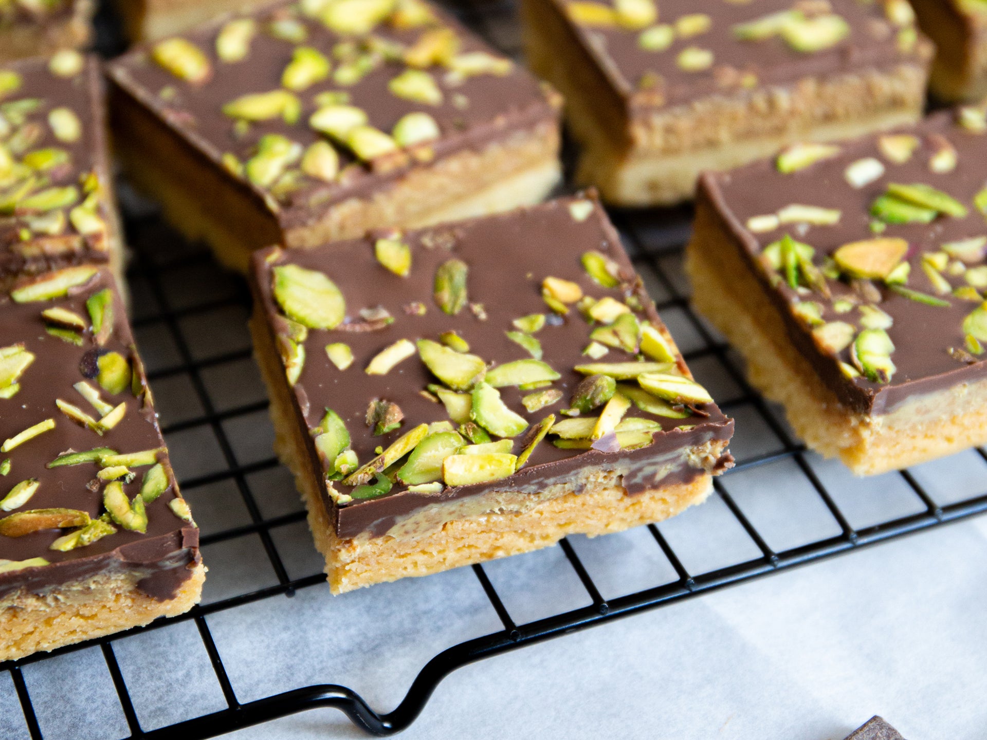 A close up of a square of chocolate & pistachio shortbread