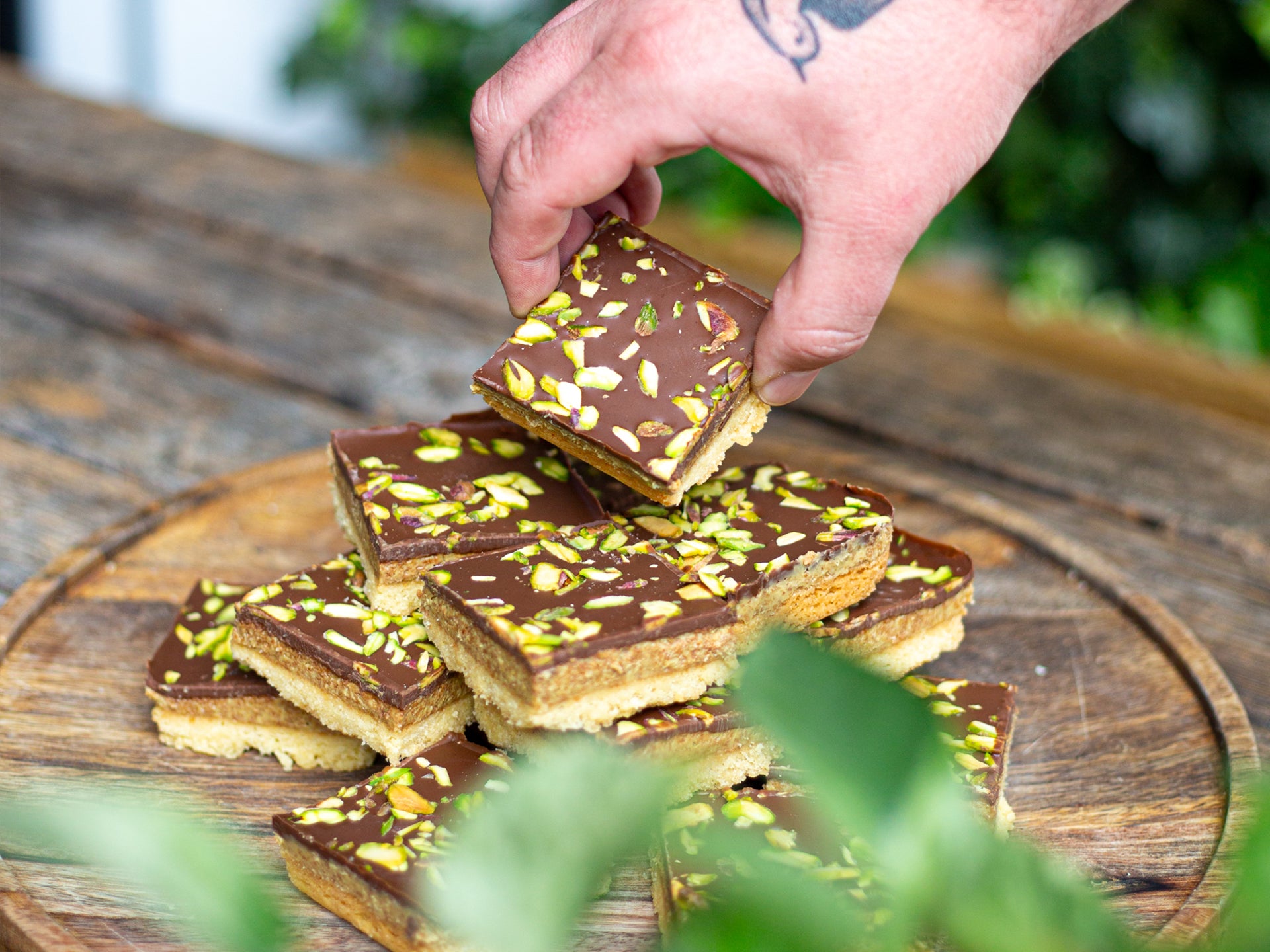 Picking up a square of chocolate & pistachio shortbread