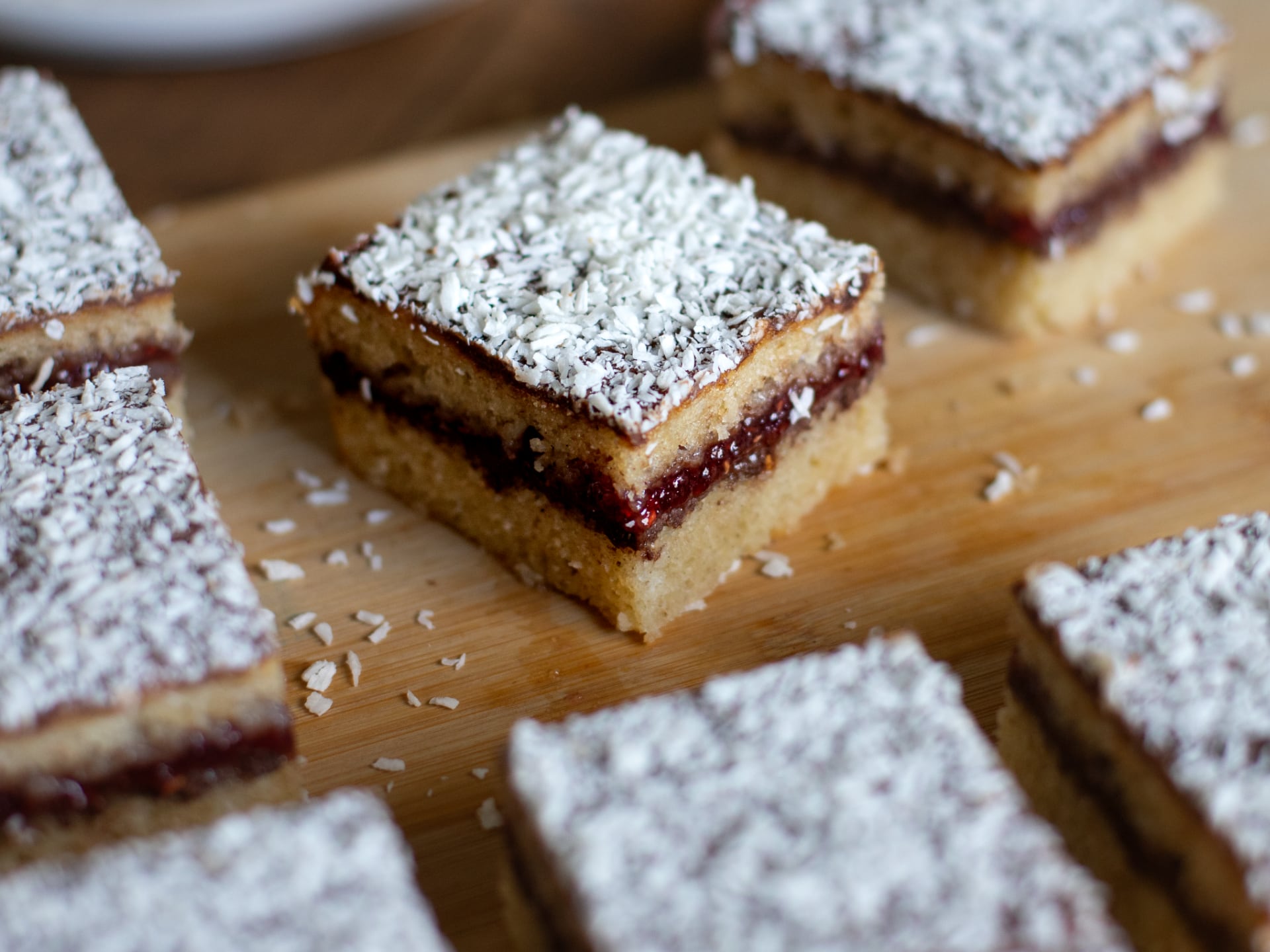 Square Chocolate Raspberry Lamington Cake , arranged on a wooden board.