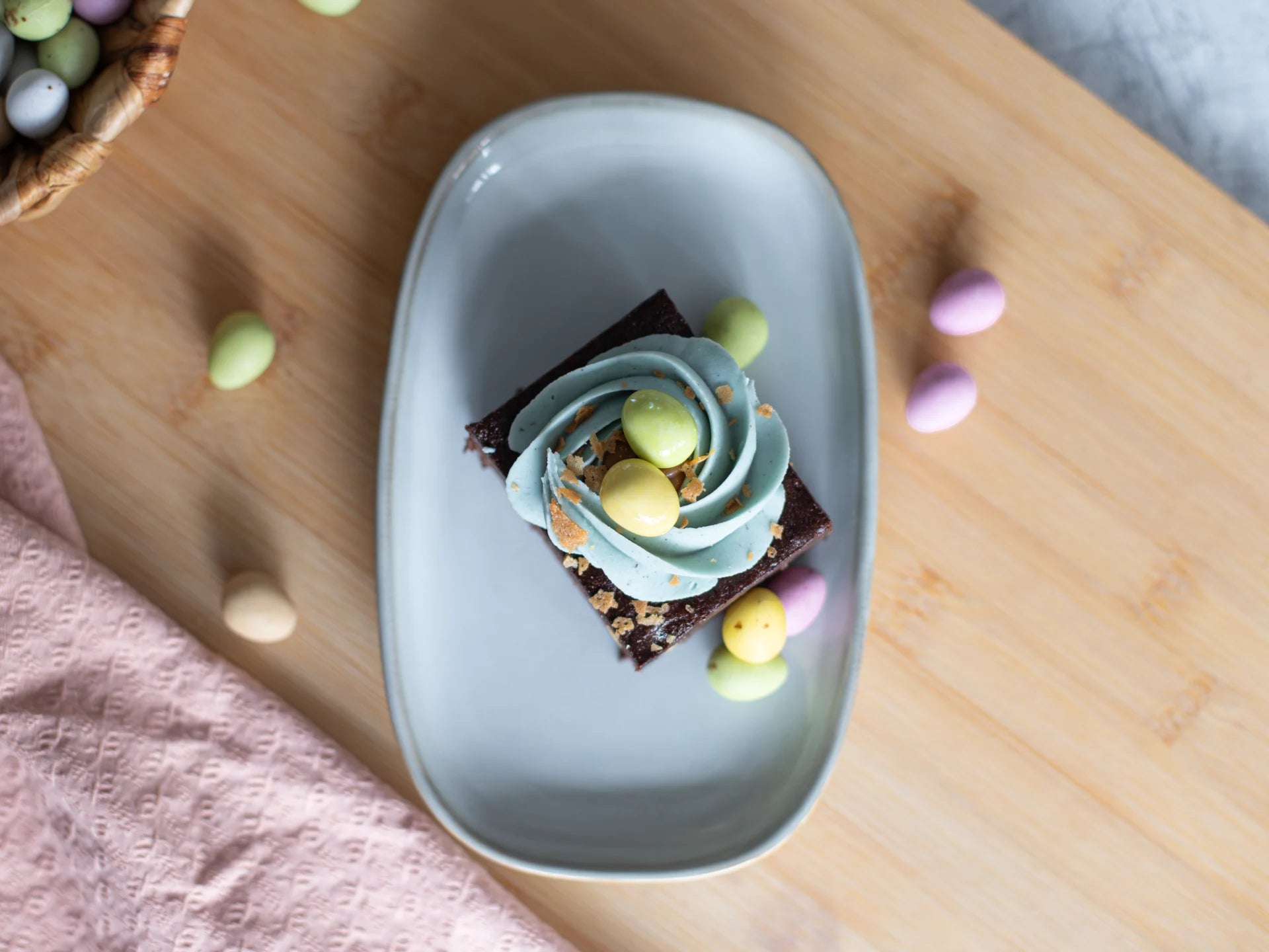 Small Chocolate Easter Nest Cake with green frosting on a light blue plate on a wooden table.
