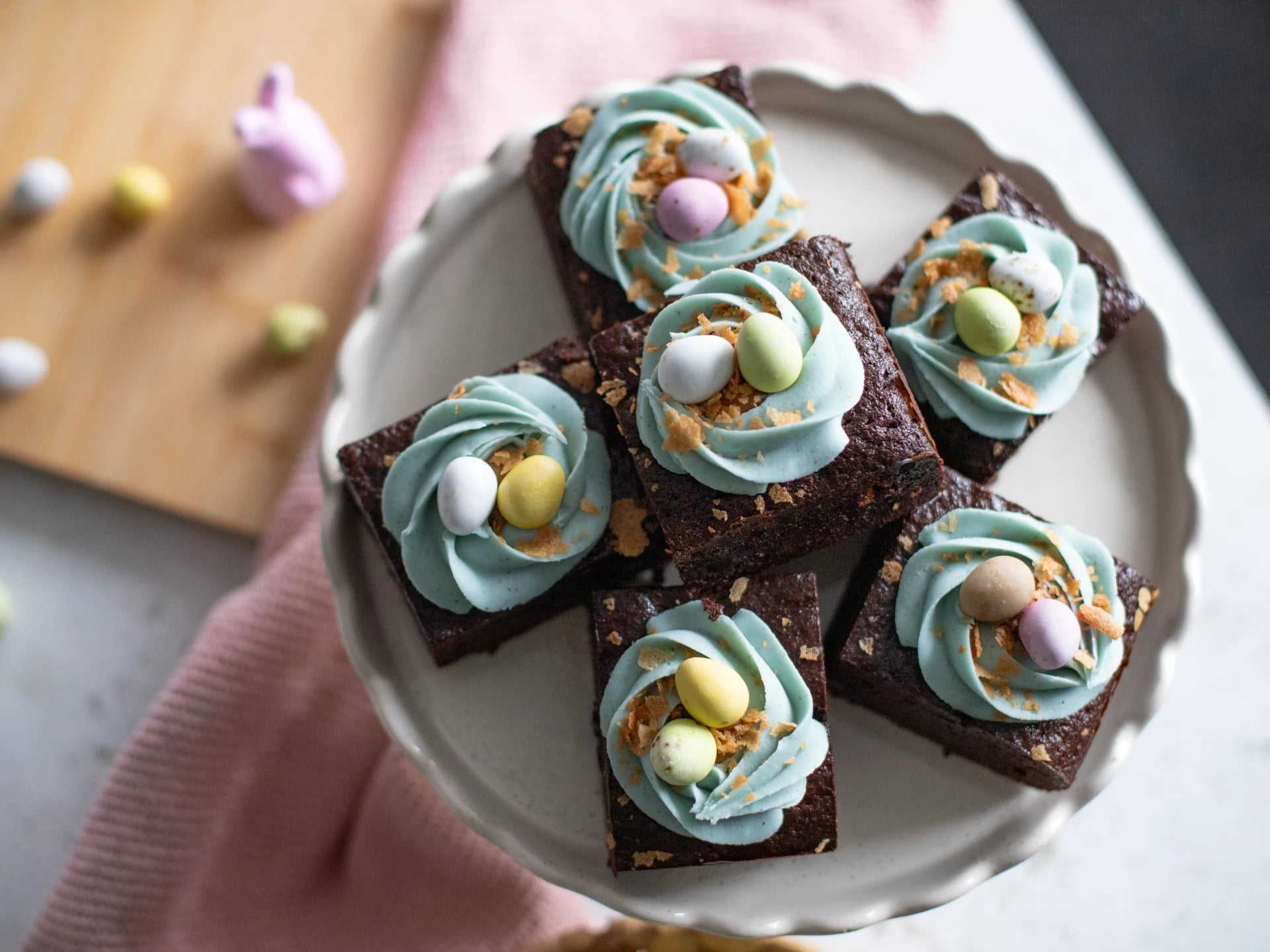 Chocolate Easter Nest Cake with blue and green frosting on a white plate, surrounded by Easter decorations.