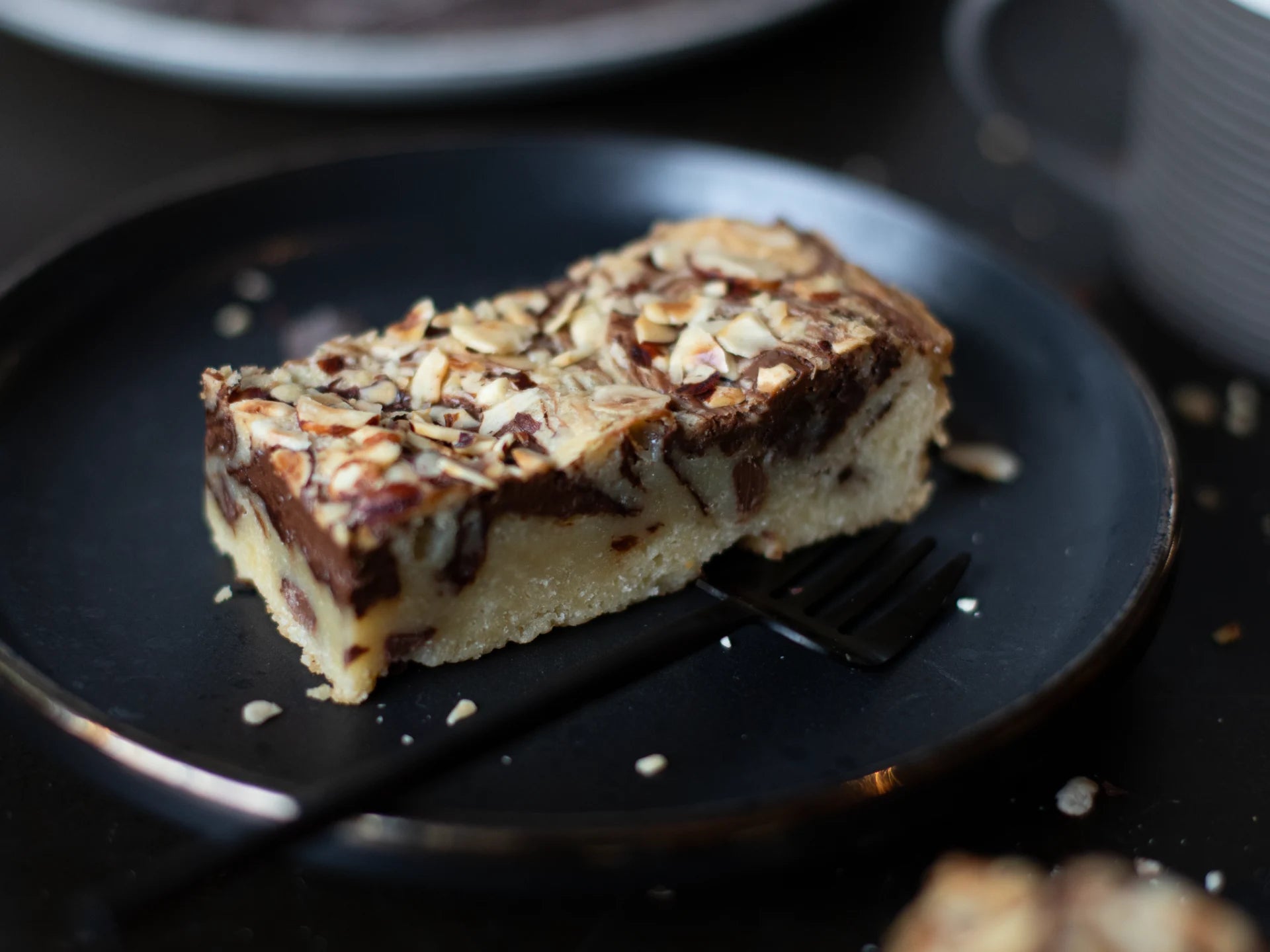 Slice of Hazelnut Blondie cake with pecans on a black plate with a fork