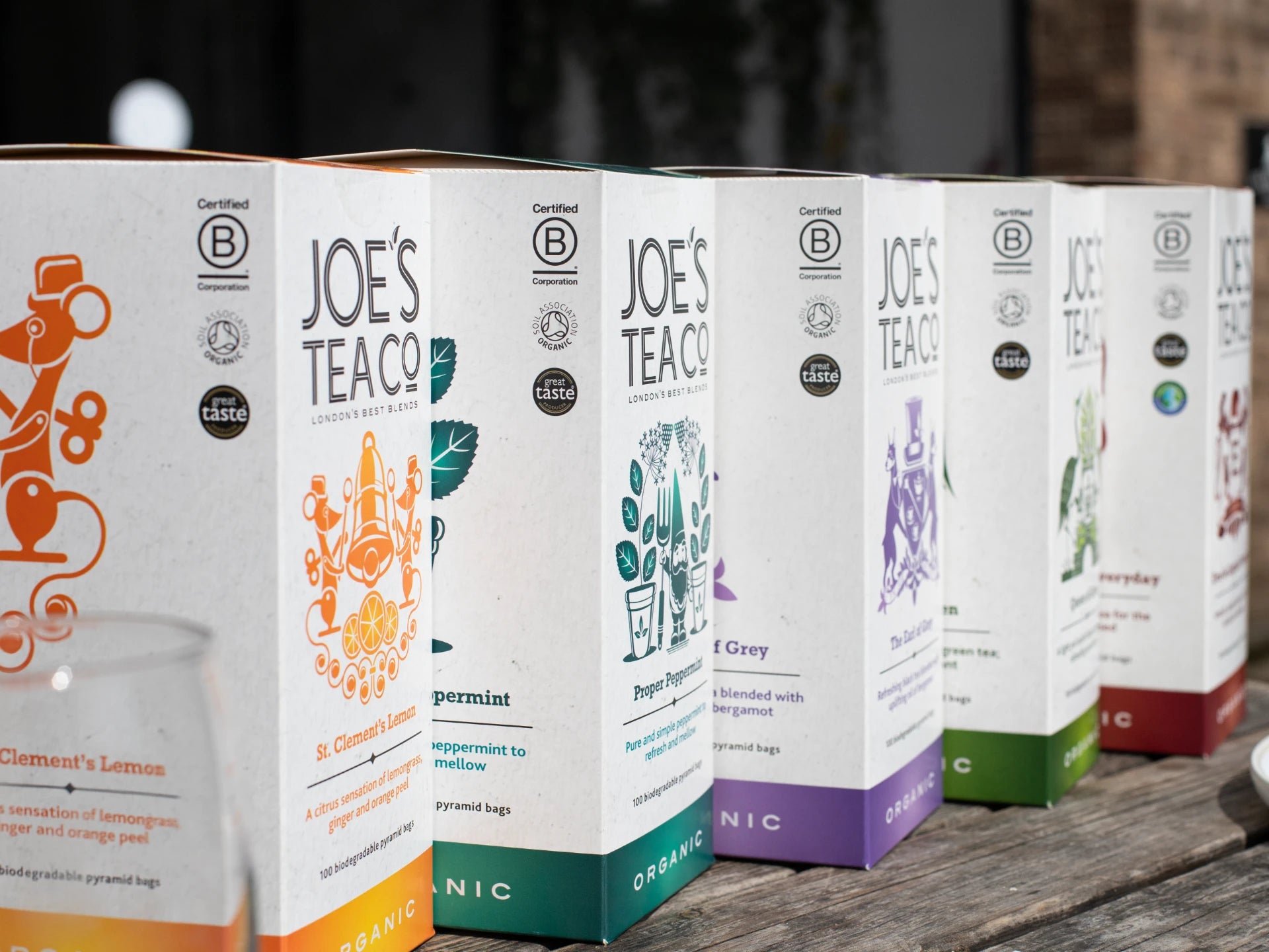 Row of Joe's Tea Co. tea boxes on a wooden surface with a blurred background