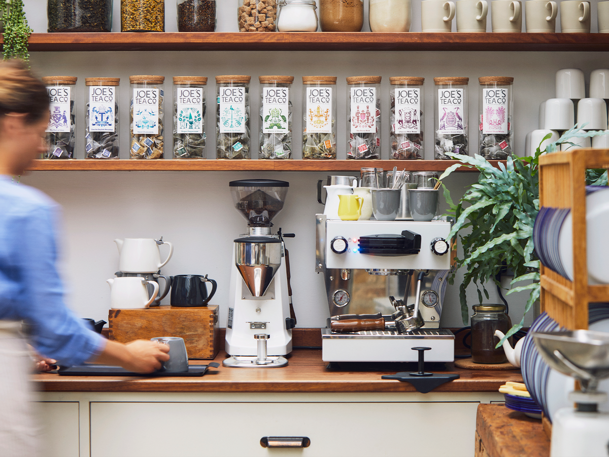 Joe's Tea co  Coffee shop interior with coffee-making equipment and shelves stocked with jars.