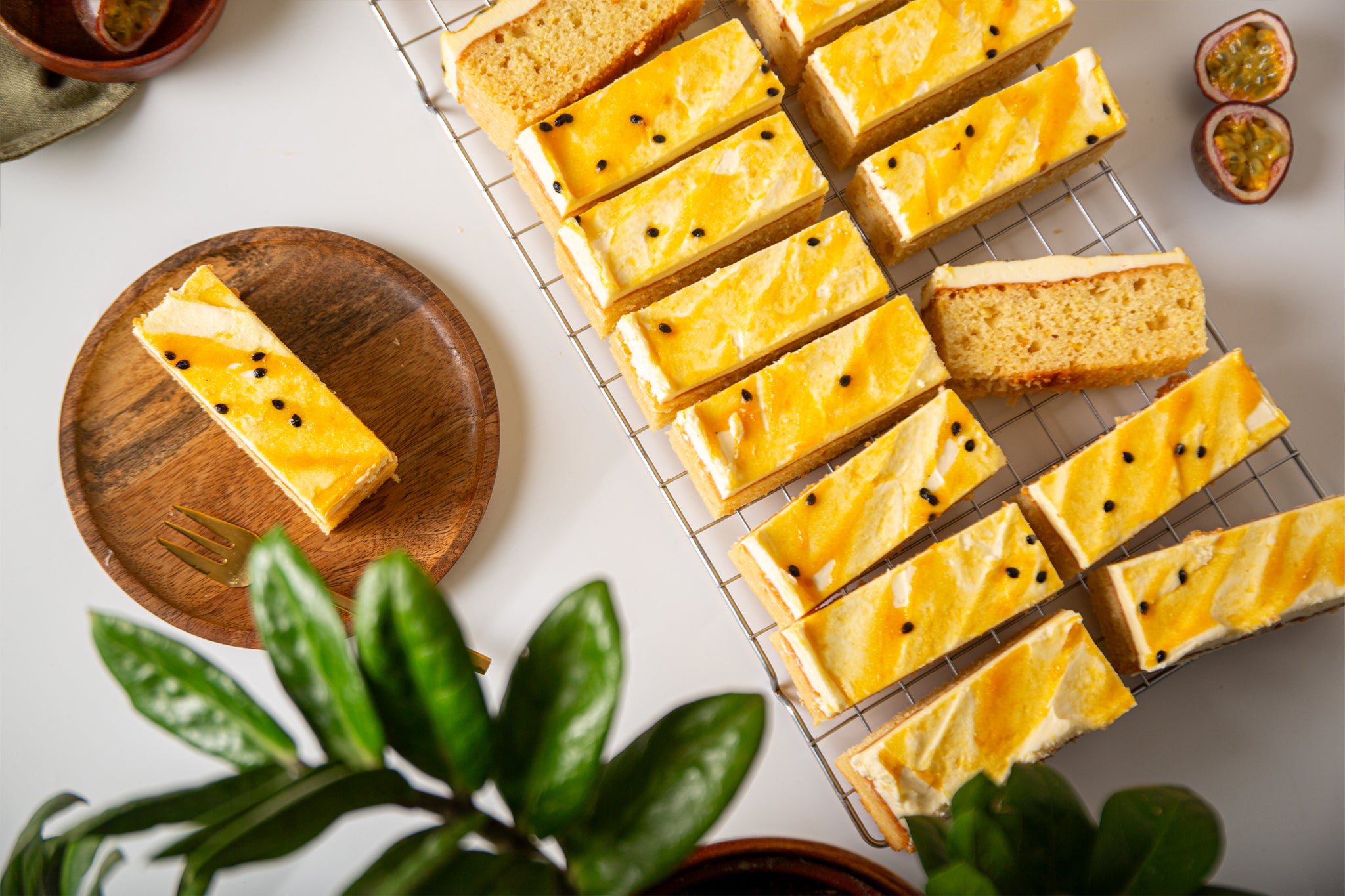 A buttermilk sponge cake with infused with passionfruit, cut into individual slices, frosted with cream cheese, and garnished with passionfruit seeds.
