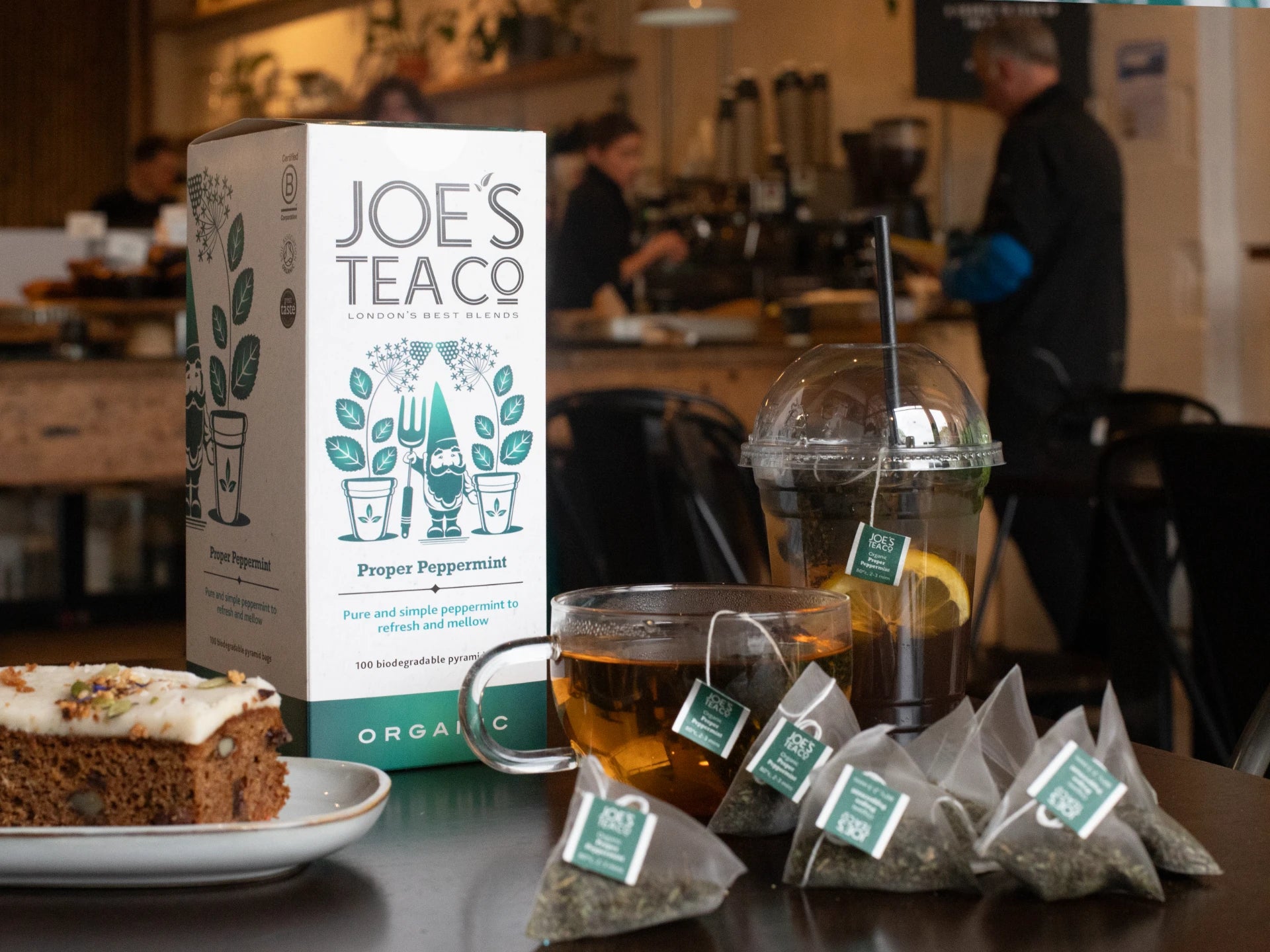 Joe's Tea Co - Proper Peppermint packaging with tea bags and a cup of tea on a table.