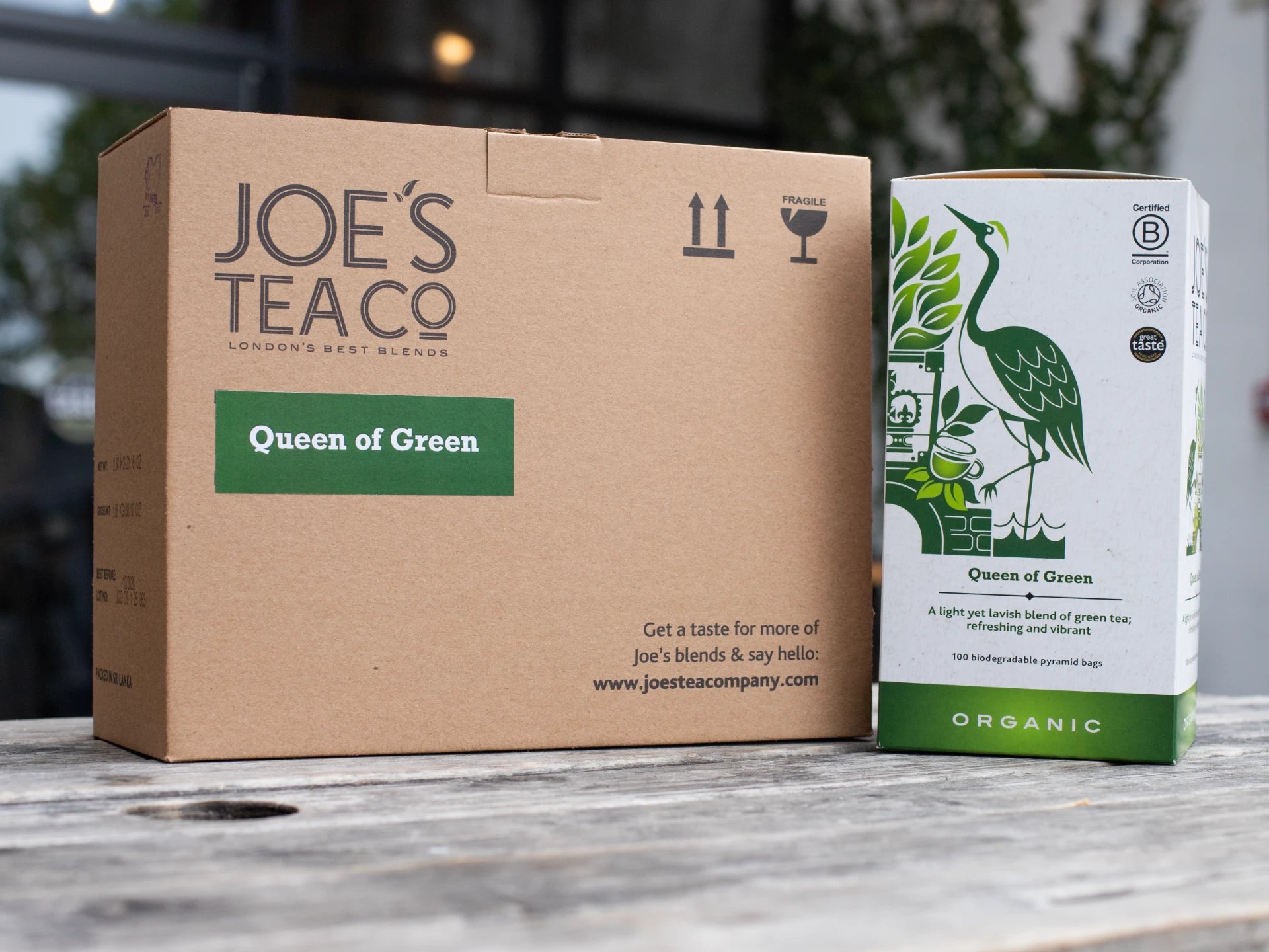 Cardboard box and tea packaging with 'Joe's Teac' branding on a wooden surface.