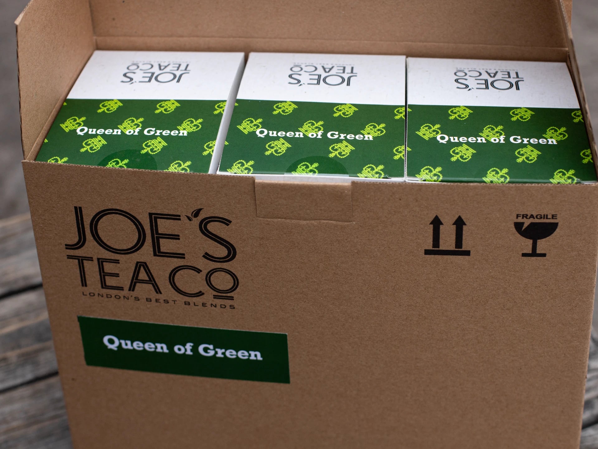 Box of Joe's Tea Co. 'Queen of Green' tea boxes on a wooden surface