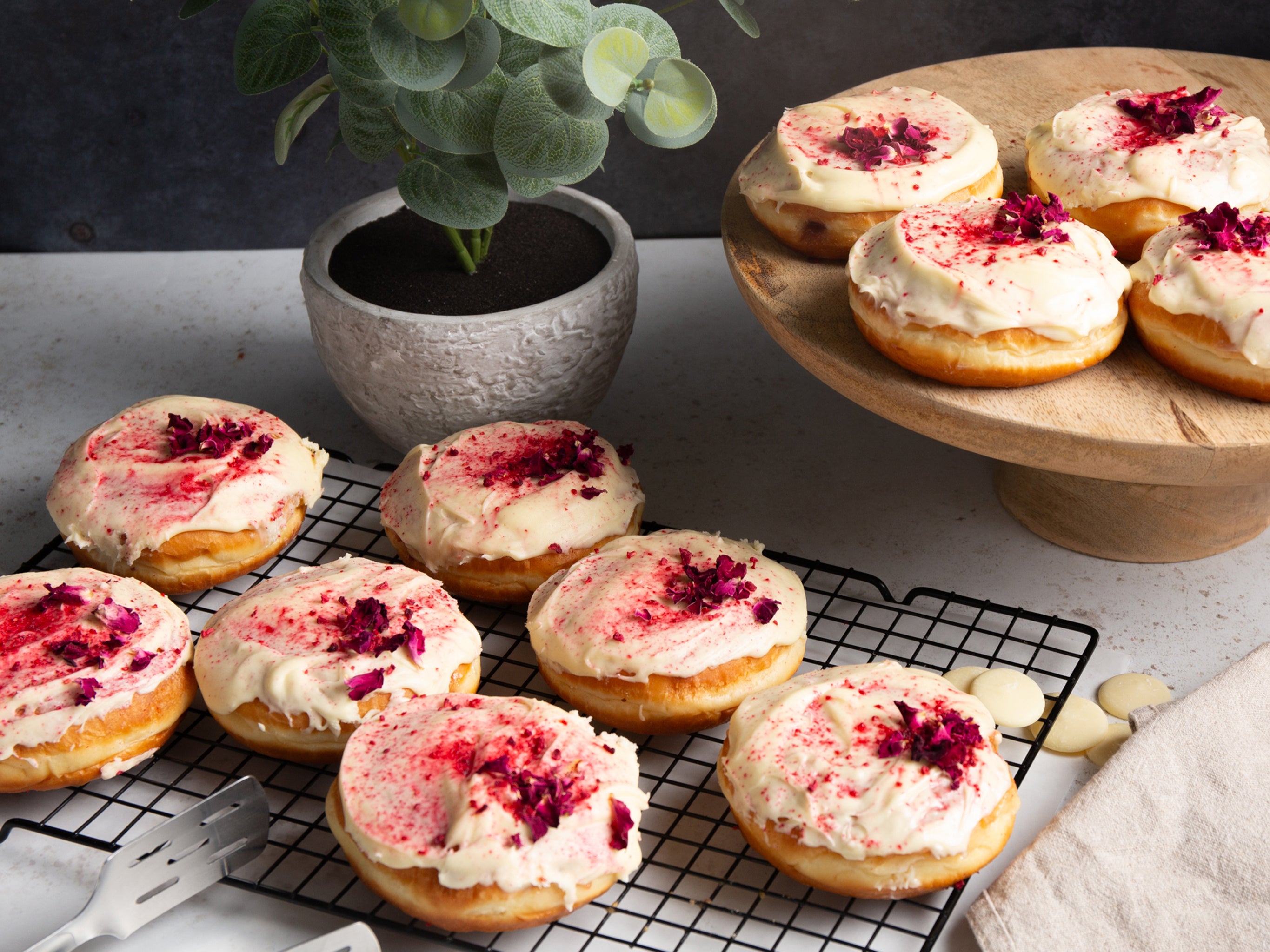 Wholesale raspberry and white chocolate doughnuts with a white choc glaze, decorated with freeze-dried raspberries and rose petals