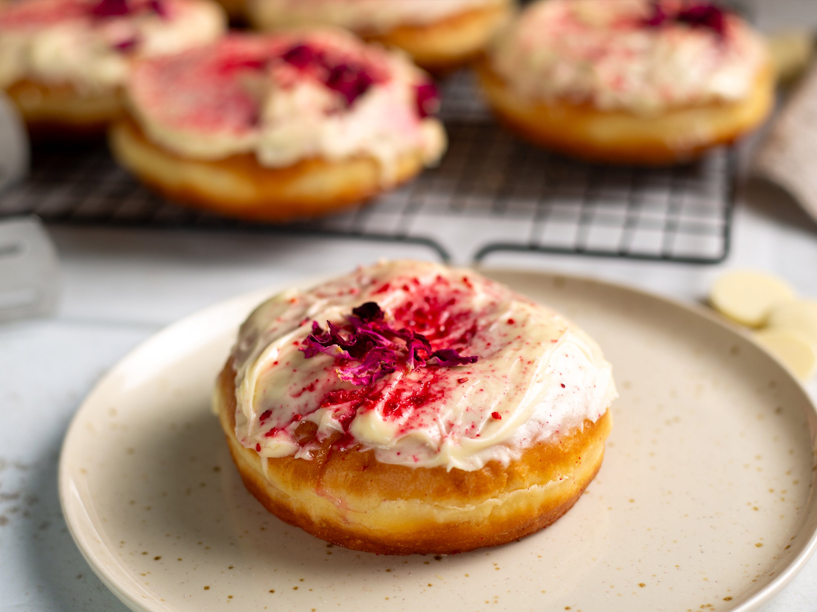 One of our wholesale vegan doughnuts filled with raspberry jam with a white choc glaze