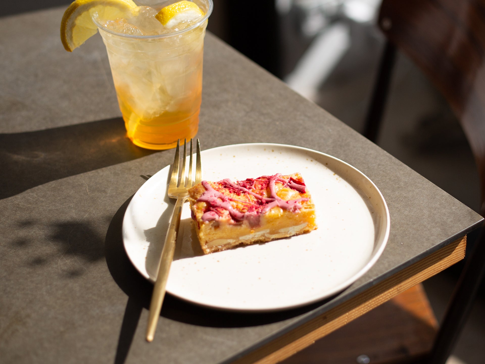 A slice of rhubarb and custard blondie with a lemon iced tea