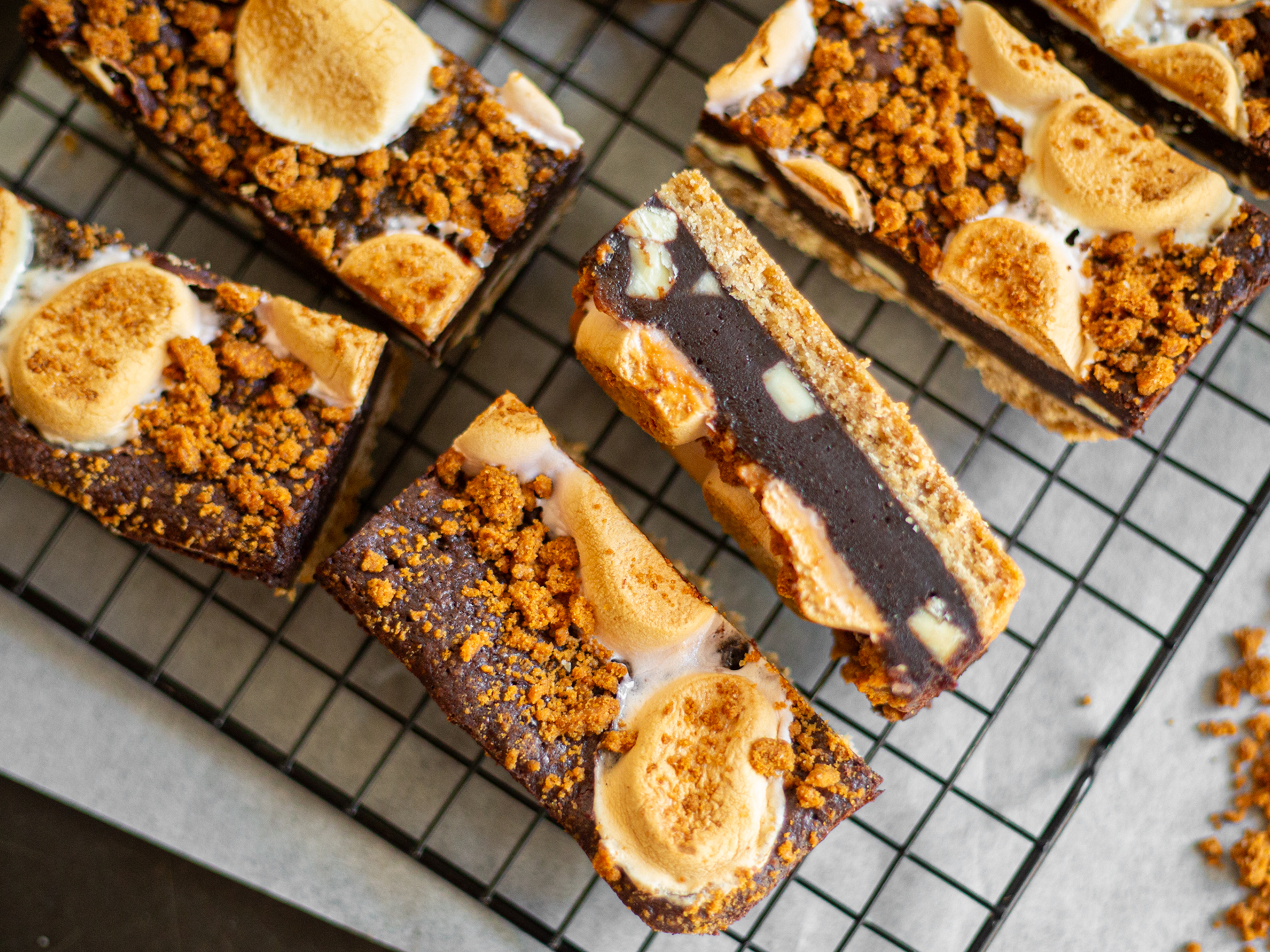S'mores brownies on a cooling rack with graham cracker crumbs and marshmallows.