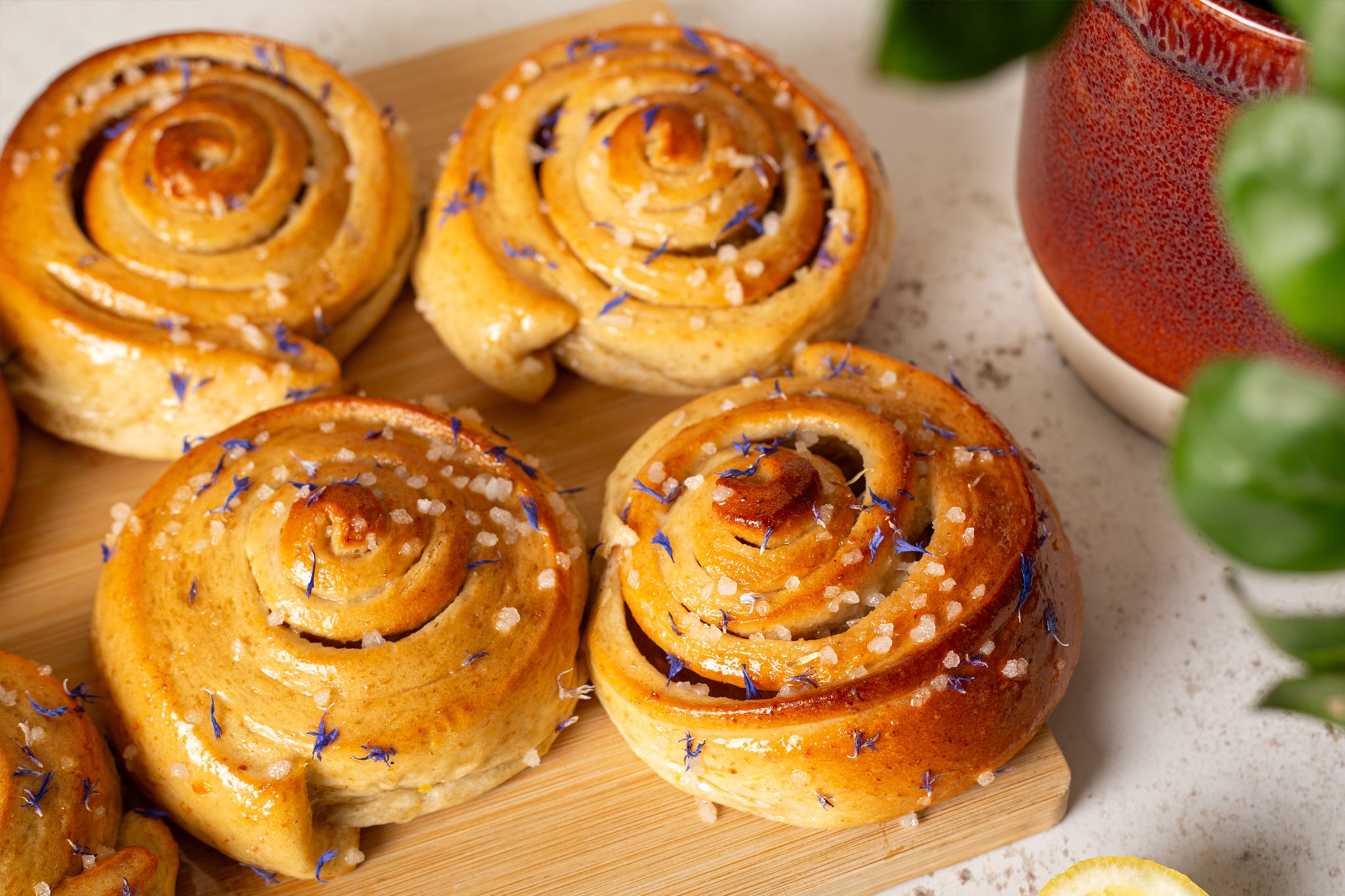 Our wholesale sticky buns are glazed with lemon drizzle and sprinkled with pearled sugar and cornflower petals