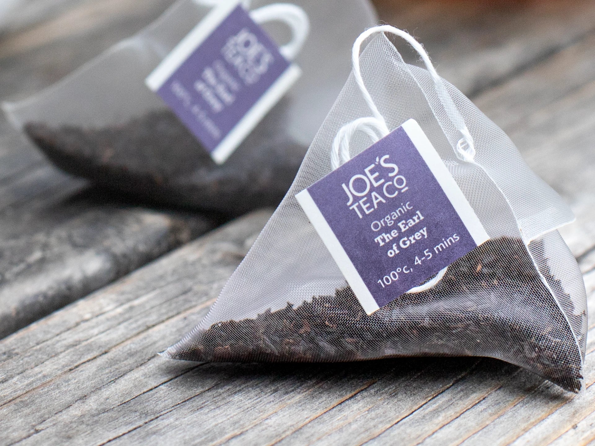 Tea bags with 'Joe's Tea Co.' labels on a wooden surface