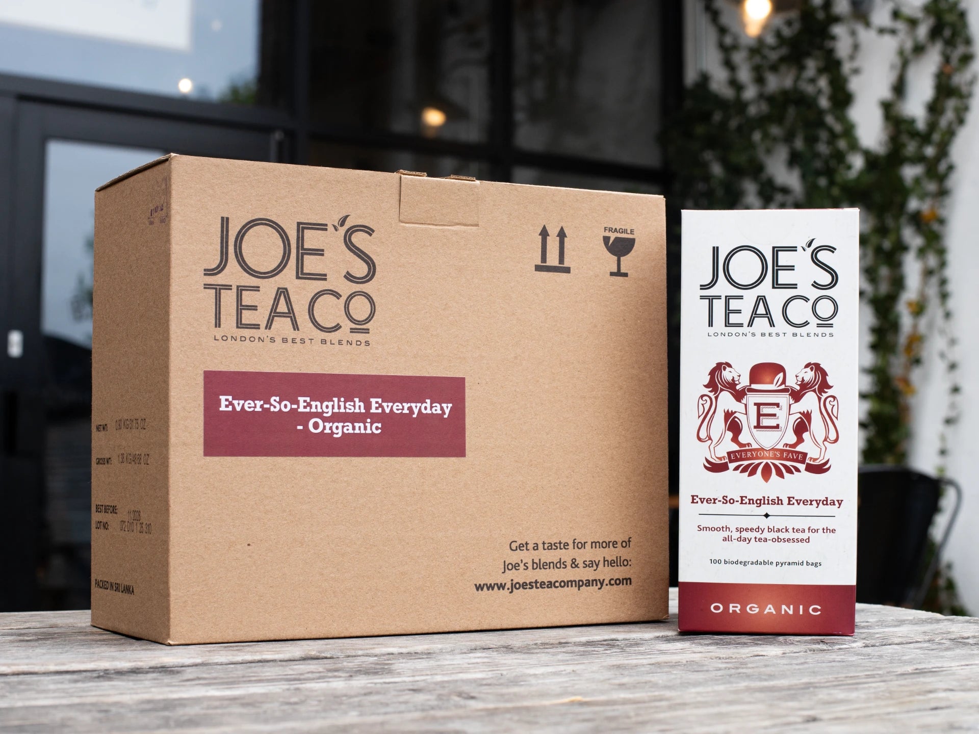 Joe's Teaco packaging including a cardboard box and a tea canister on a wooden surface.