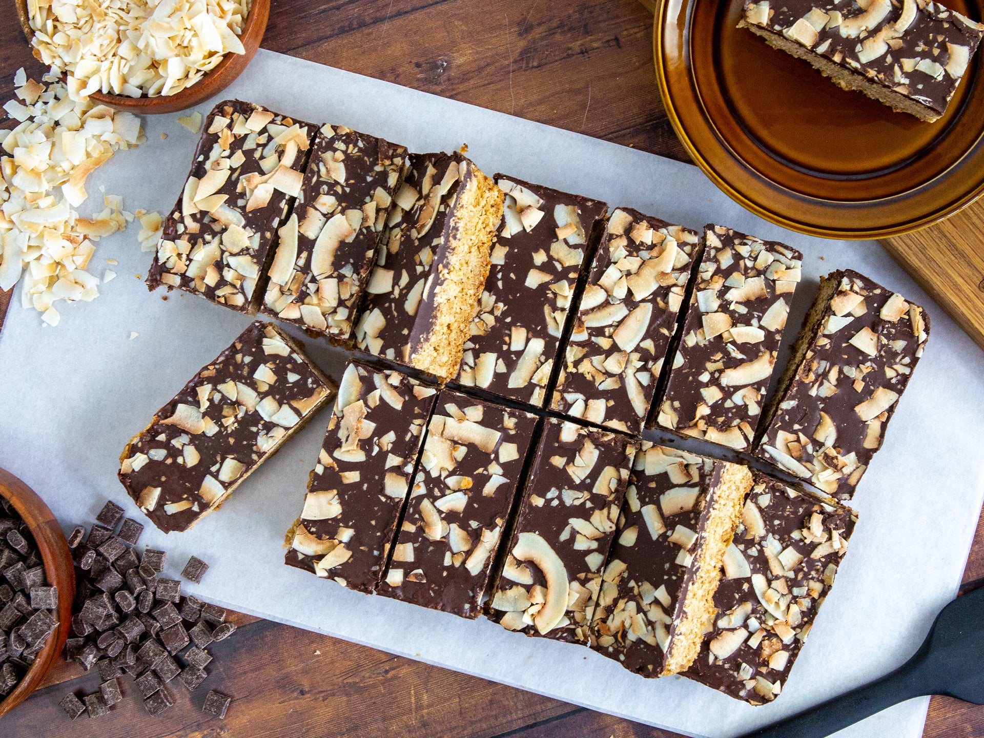 A board filled with slices of toasted coconut and dark chocolate flapjack