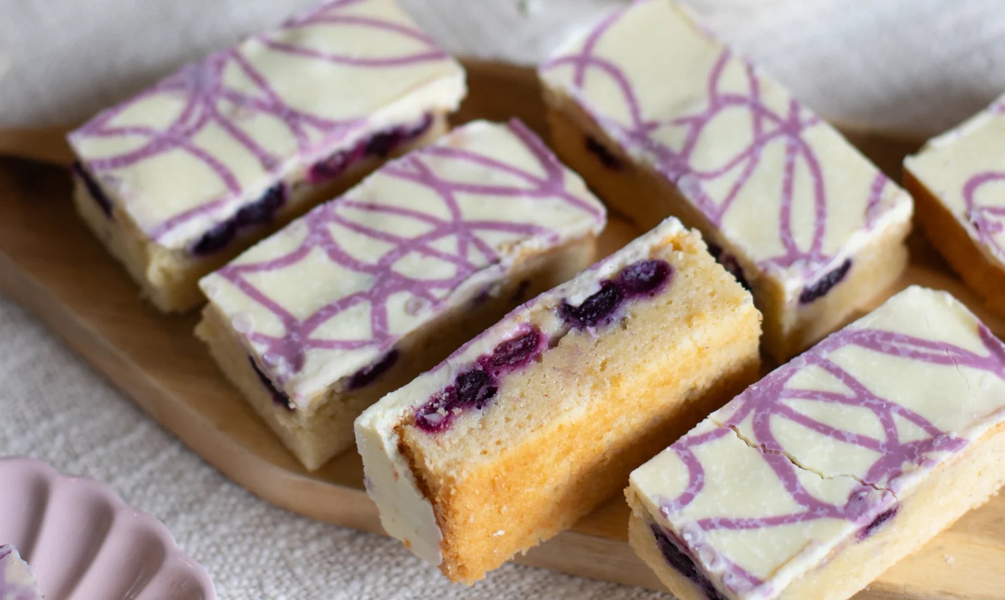 Baked goods with purple drizzle on a wooden plate