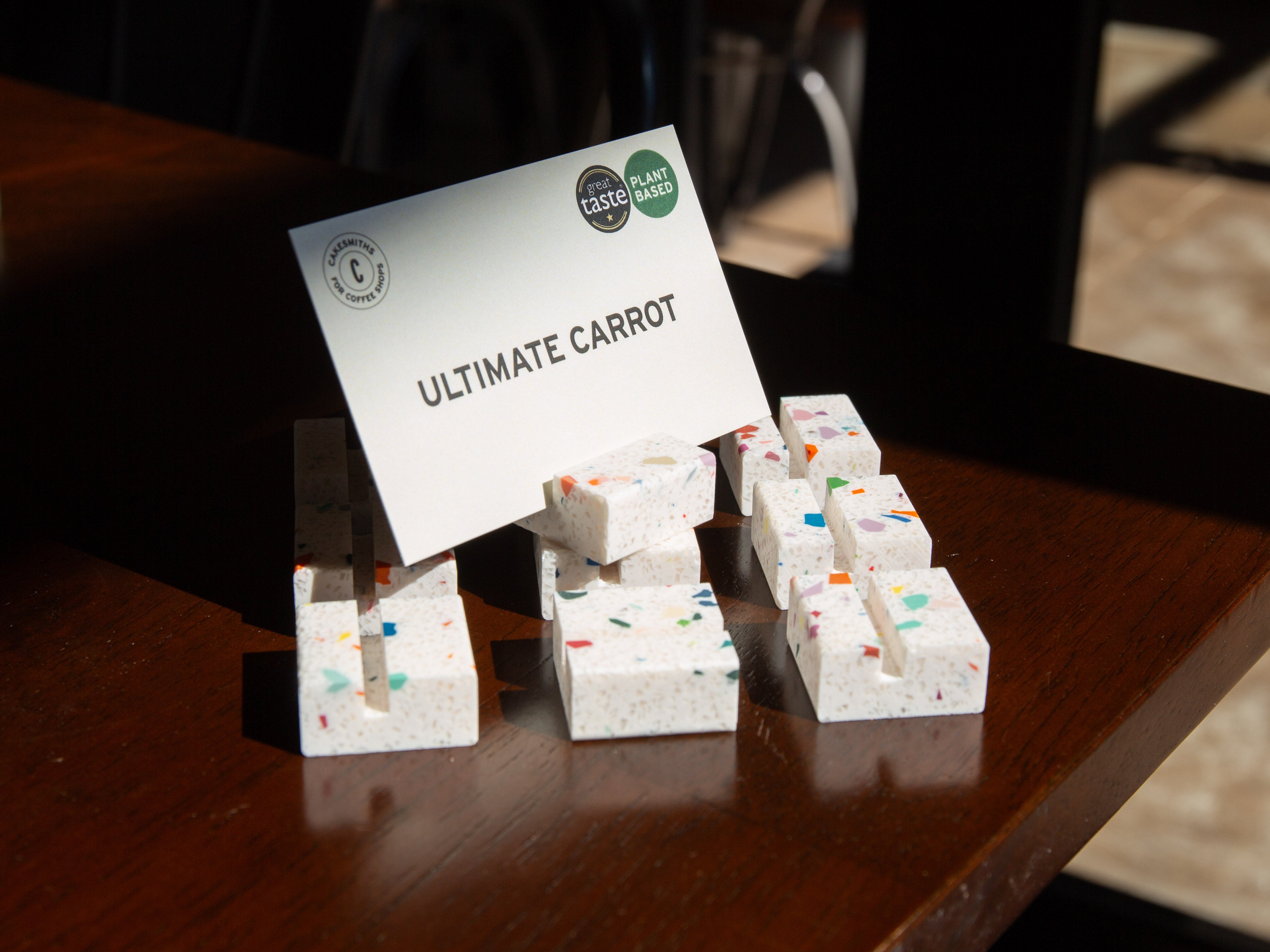Confetti Product Display Card Stands with a sign labeled 'Ultimate Carrot' on a wooden surface.